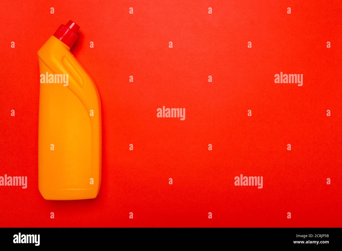 Gelbe Toilettenreiniger auf rotem Hintergrund. Copyspace Stockfoto