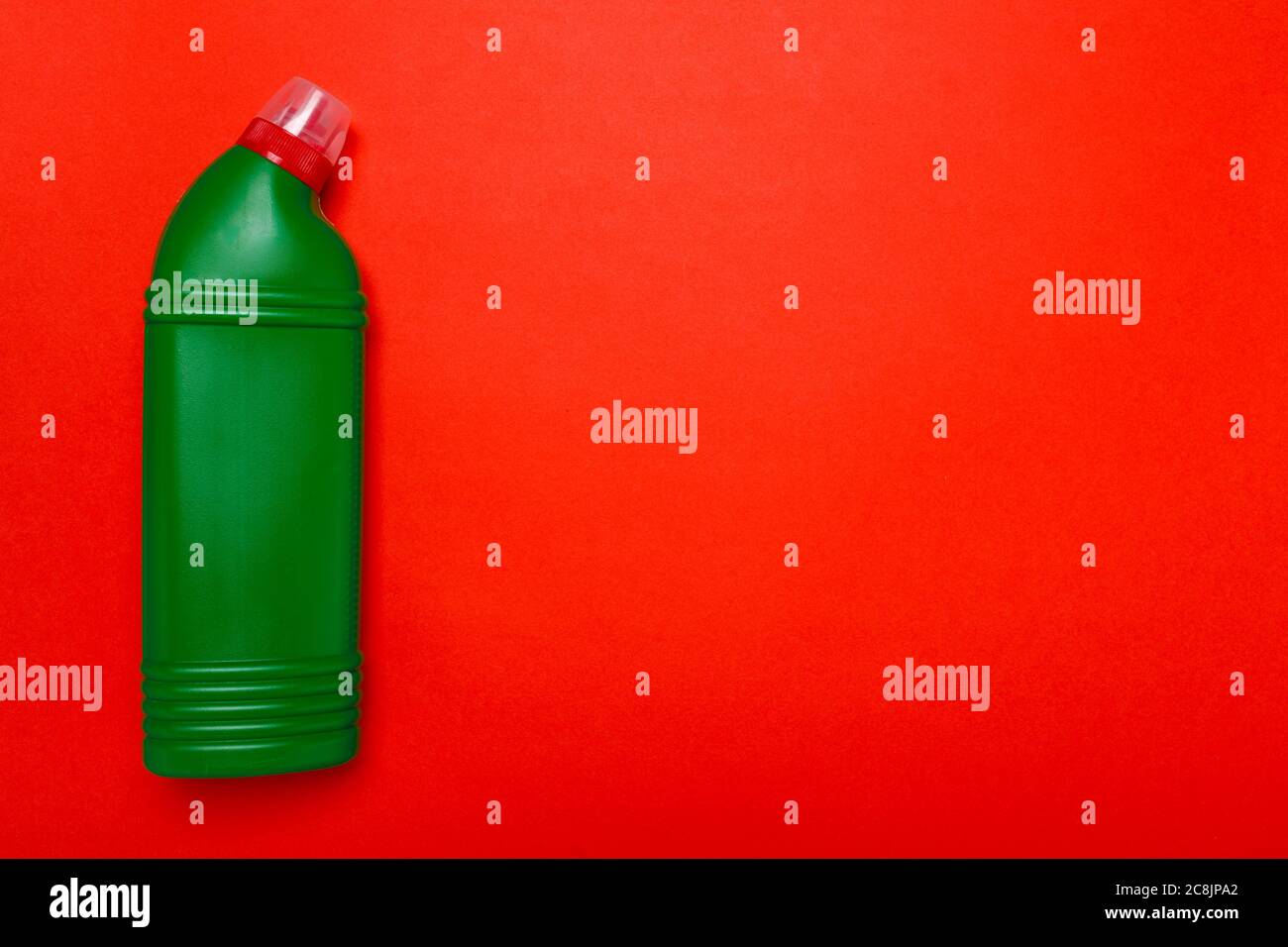 Grüner Toilettenreiniger auf rotem Hintergrund. Copyspace Stockfoto