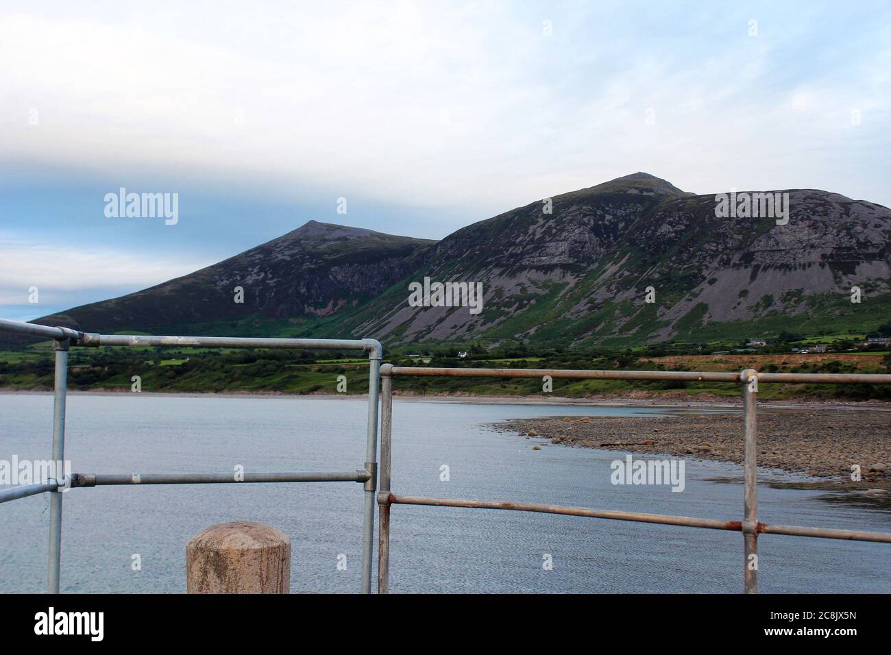 Blick auf die Rivals Mountains (Yr Eifl) von einem Pier / Meer Gehweg, einschließlich der Barrieren, in Trefor, Nordwales Stockfoto