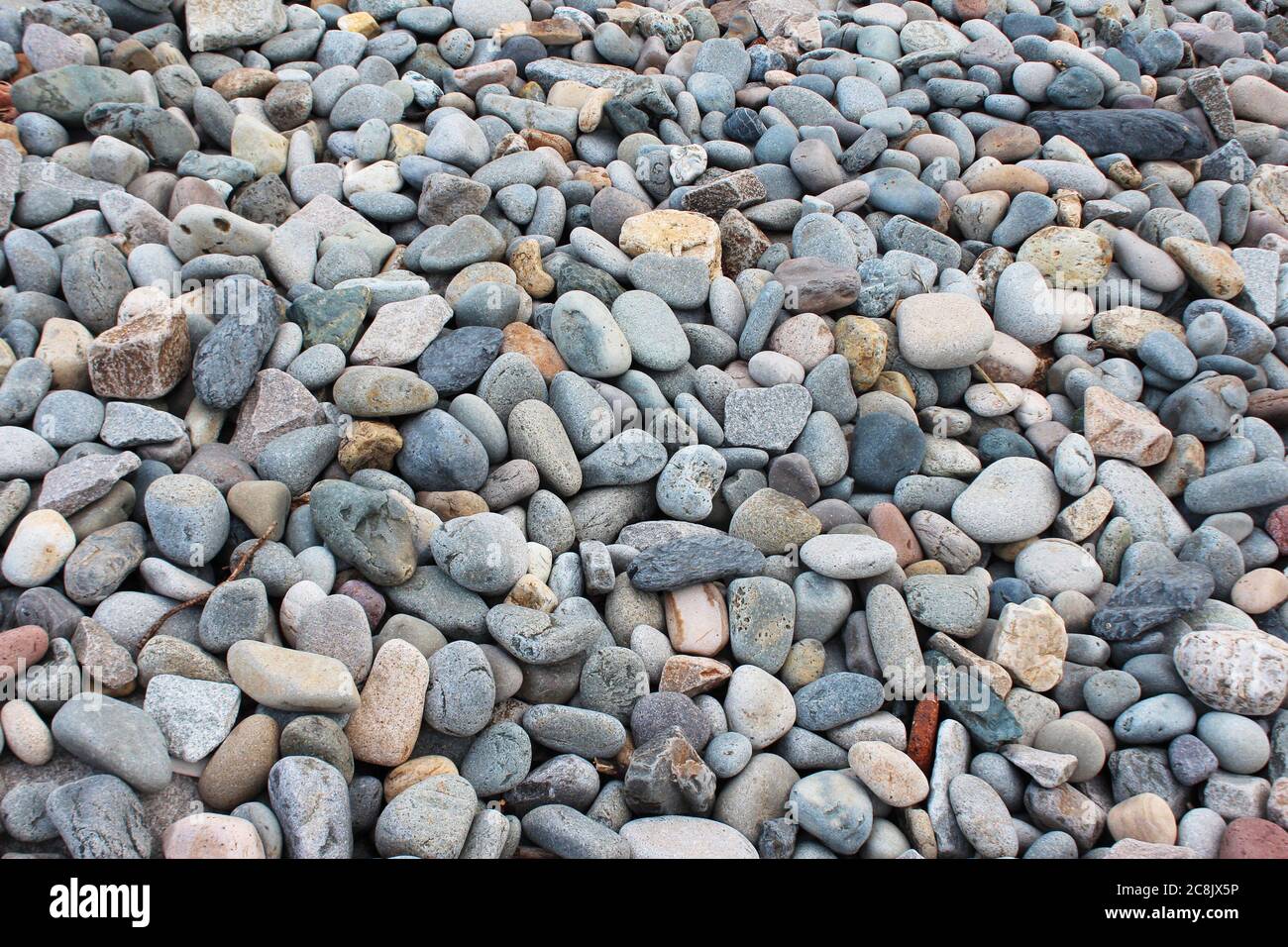 Steine, Felsen und Kieselsteine an einem felsigen Strand in Trefor, Nordwales Stockfoto