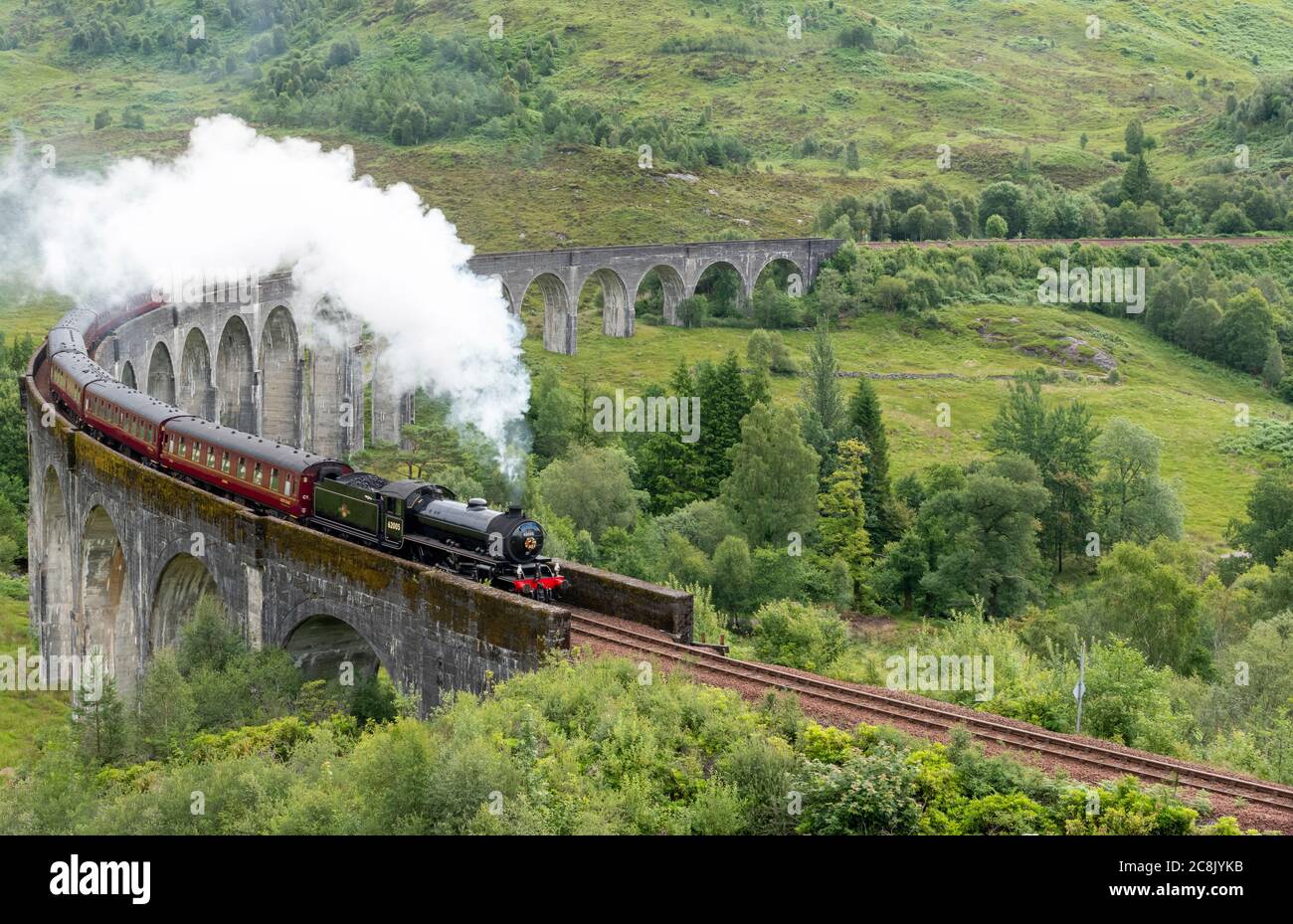 JACOBITE DAMPFZUG WEST HIGHLAND LINIE SCHOTTLAND IM SOMMER ZUG UND WOLKE VON WEISSEM RAUCH AUS DEM TRICHTER, WIE ES DAS ENDE DES GLENFINNAN VIADUKT ÜBERQUERT Stockfoto