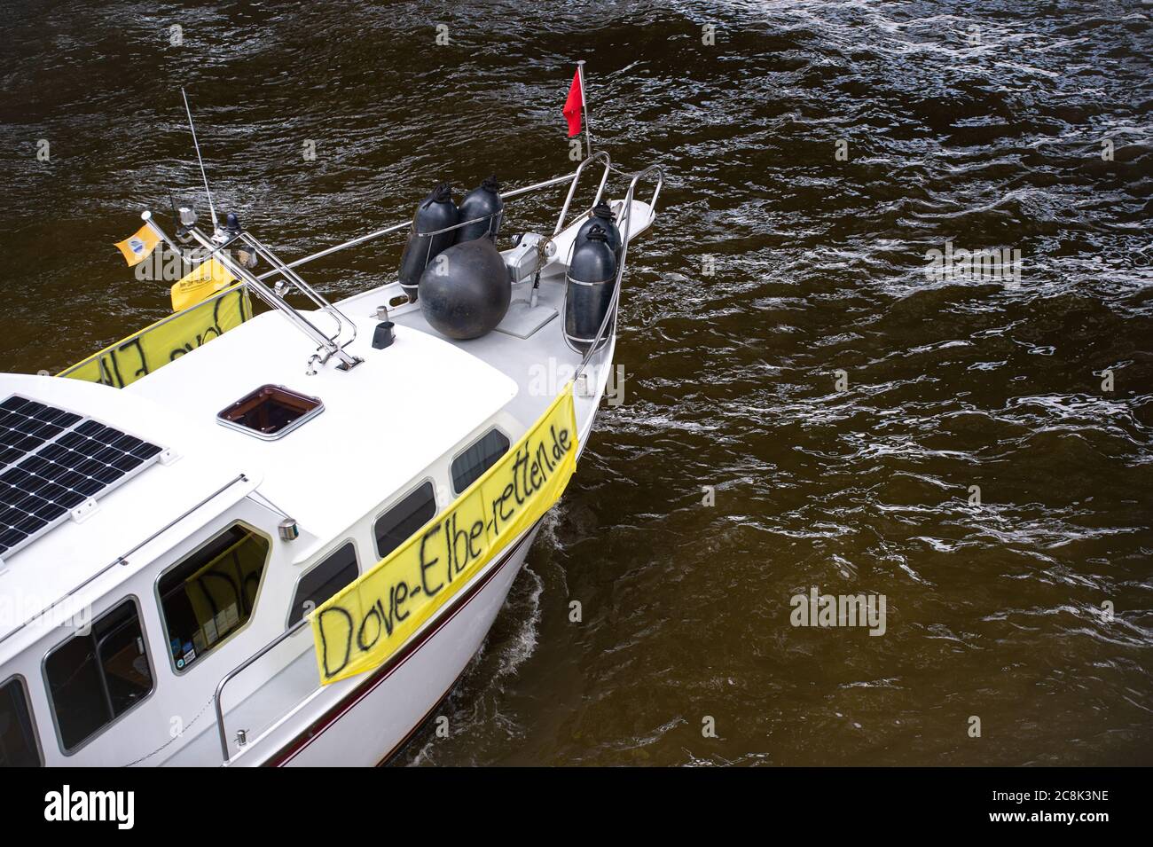 25. Juli 2020, Hamburg: Ein Plakat mit der Aufschrift 'ove-Elbe-retten.de' ist an einem Motorboot angebracht, das auf der Elbe fährt. 100 Boote seien bei einer Demonstration der Bürgerinitiative "Dove-Elbe-Retten" nach Angaben der Polizei in Richtung der Landestreben gestartet. Die Demonstration richtete sich nach Angaben der Initiatoren gegen Überlegungen, die Taubenelbe an der Tatenberger Schleuse in Richtung Norderelbe zu öffnen und damit zu einem Gezeitenwasser zu machen. Dies würde lokale Vereine und Unternehmen sowie die Flora und Fauna bedrohen. Foto: Jonas Walzberg/dpa Stockfoto