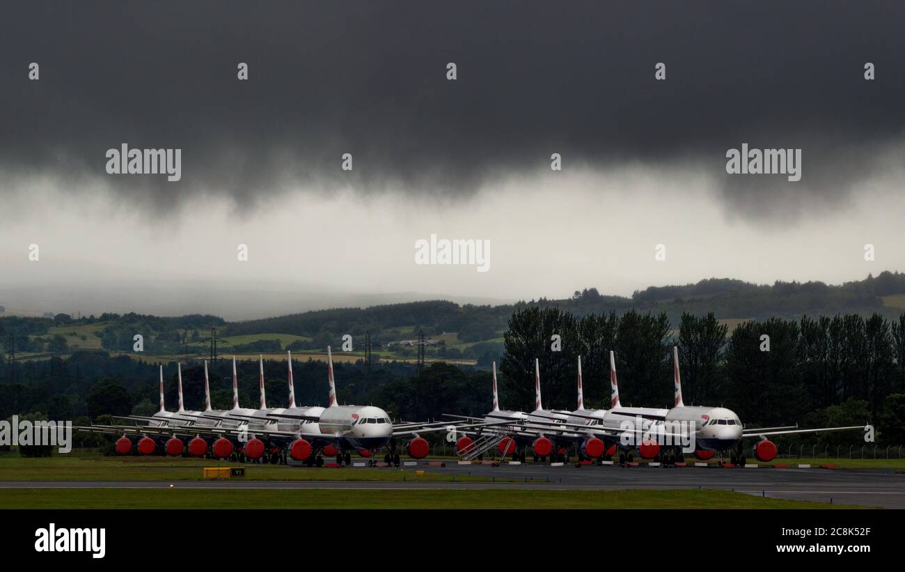 Glasgow, Schottland, Großbritannien. 23. Juli 2020. Im Bild: Unter einer drohenden dunklen, stürmischen Wolke sitzen die geerdeten Flugzeuge des Typs British Airways (BA) Airbus A319/A320/A321 auf der zweiten Landebahn des Flughafens Glasgow und warten darauf, verkauft oder gelagert zu werden. Seit März sitzen diese Flugzeuge auf dem Asphalt der Flughäfen untätig, was der weltweiten Krise des Coronavirus (COVID19) zusteht. British Airways hat fast 12,000 Mitarbeiter gekürzt und bis heute ihre gesamte Boeing 747-Flotte in den Ruhestand, um die Betriebskosten zu senken. Quelle: Colin Fisher/Alamy Live News. Stockfoto
