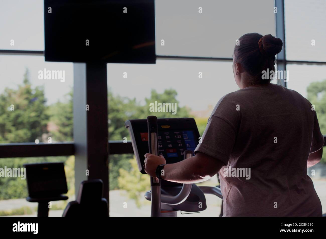 Frau auf dem Step-Gerät im Fitnessstudio mit Blick aus dem Fenster Stockfoto