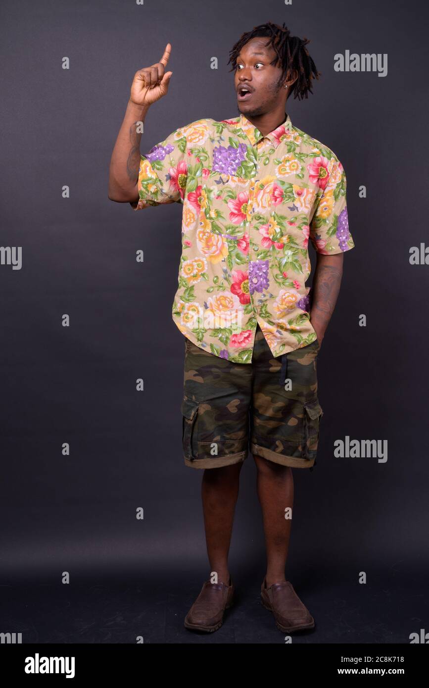 Junger Afrikaner mit Dreadlocks vor schwarzem Hintergrund Stockfoto