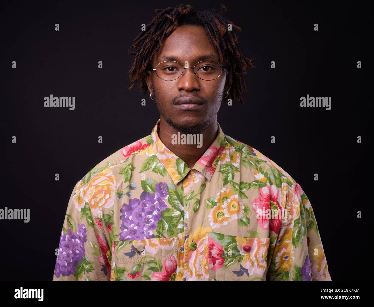 Junger Afrikaner mit Dreadlocks vor schwarzem Hintergrund Stockfoto