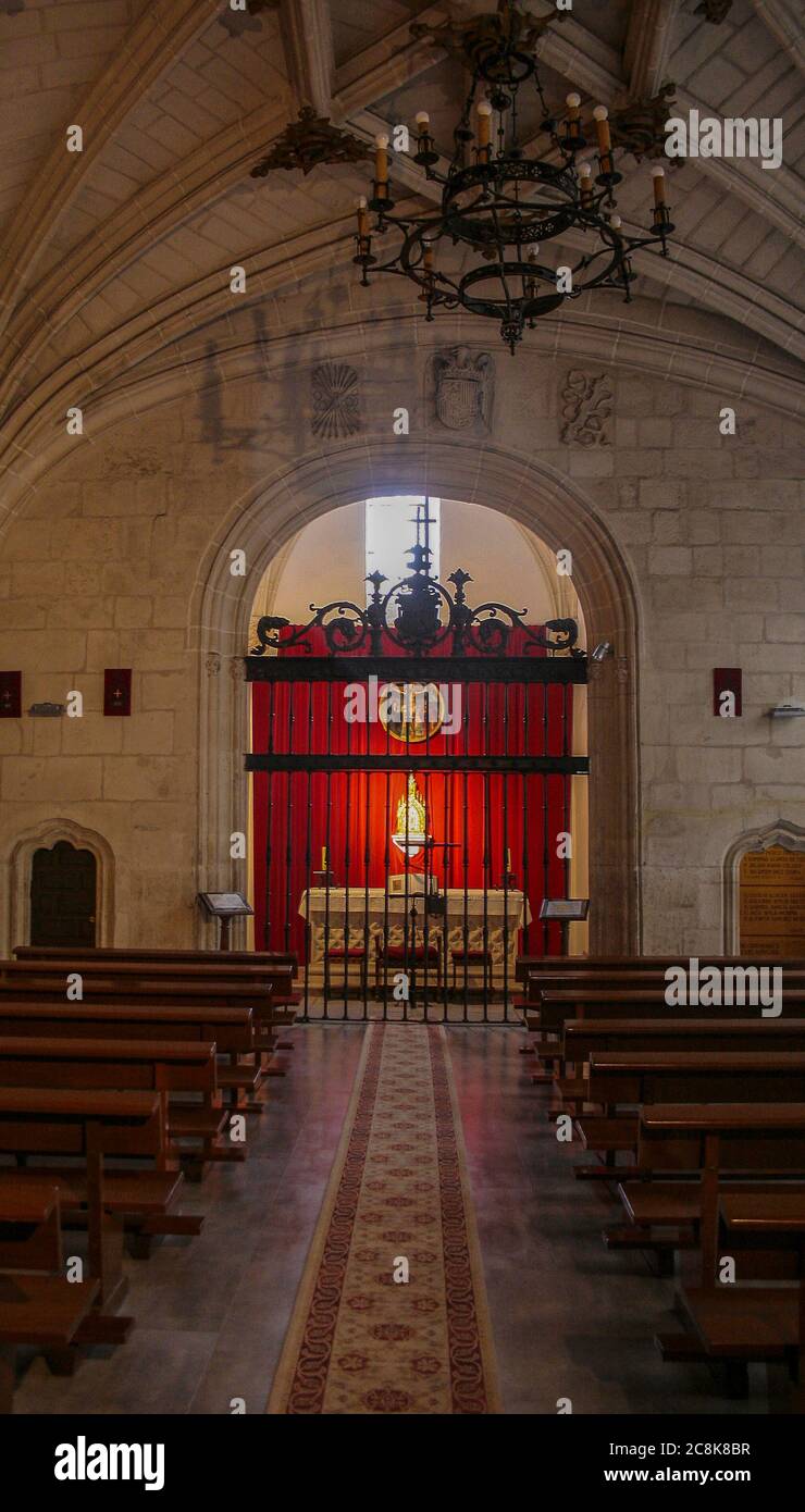 Toledo, Castilla-La Mancha, Spanien, Europa. Kloster San Juan de los Reyes ((14771504). Das Innere der Kirche. Kapelle des Santisimo, rotes Tuch mit Tabernakel und Gemälde "Kalvarienberg", von Juan Correa de Vivar (1510-1566), Maler von Toledo, Zeichnung Jesus Christus am Kreuz, mit zu seinen Füßen die Jungfrau Maria und St. Johannes der Apostel. Stockfoto