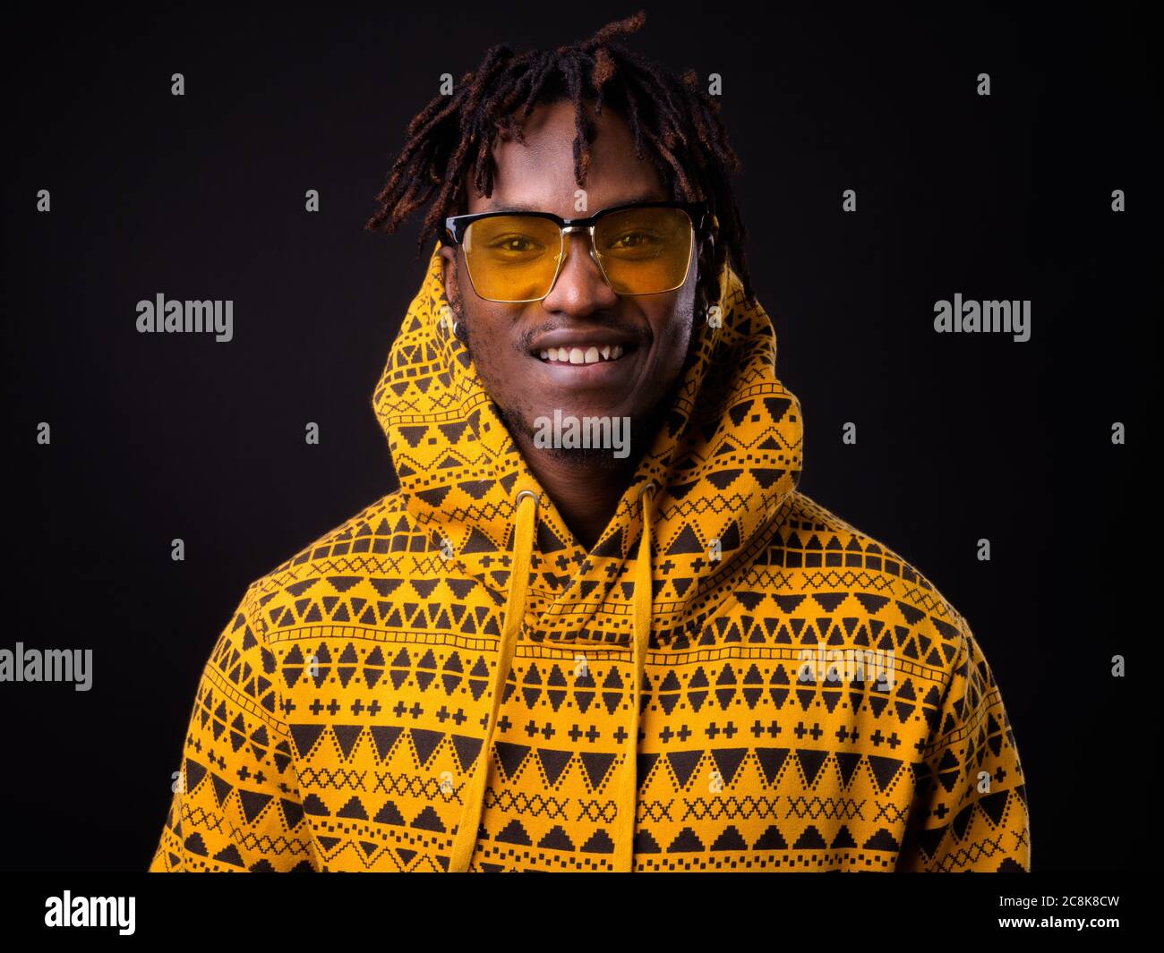 Junger Afrikaner mit Dreadlocks vor schwarzem Hintergrund Stockfoto