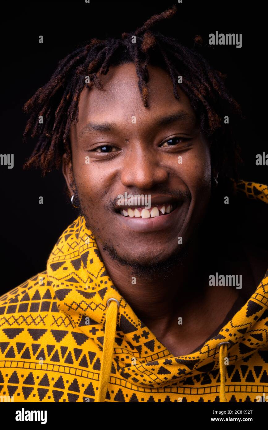 Junger Afrikaner mit Dreadlocks vor schwarzem Hintergrund Stockfoto