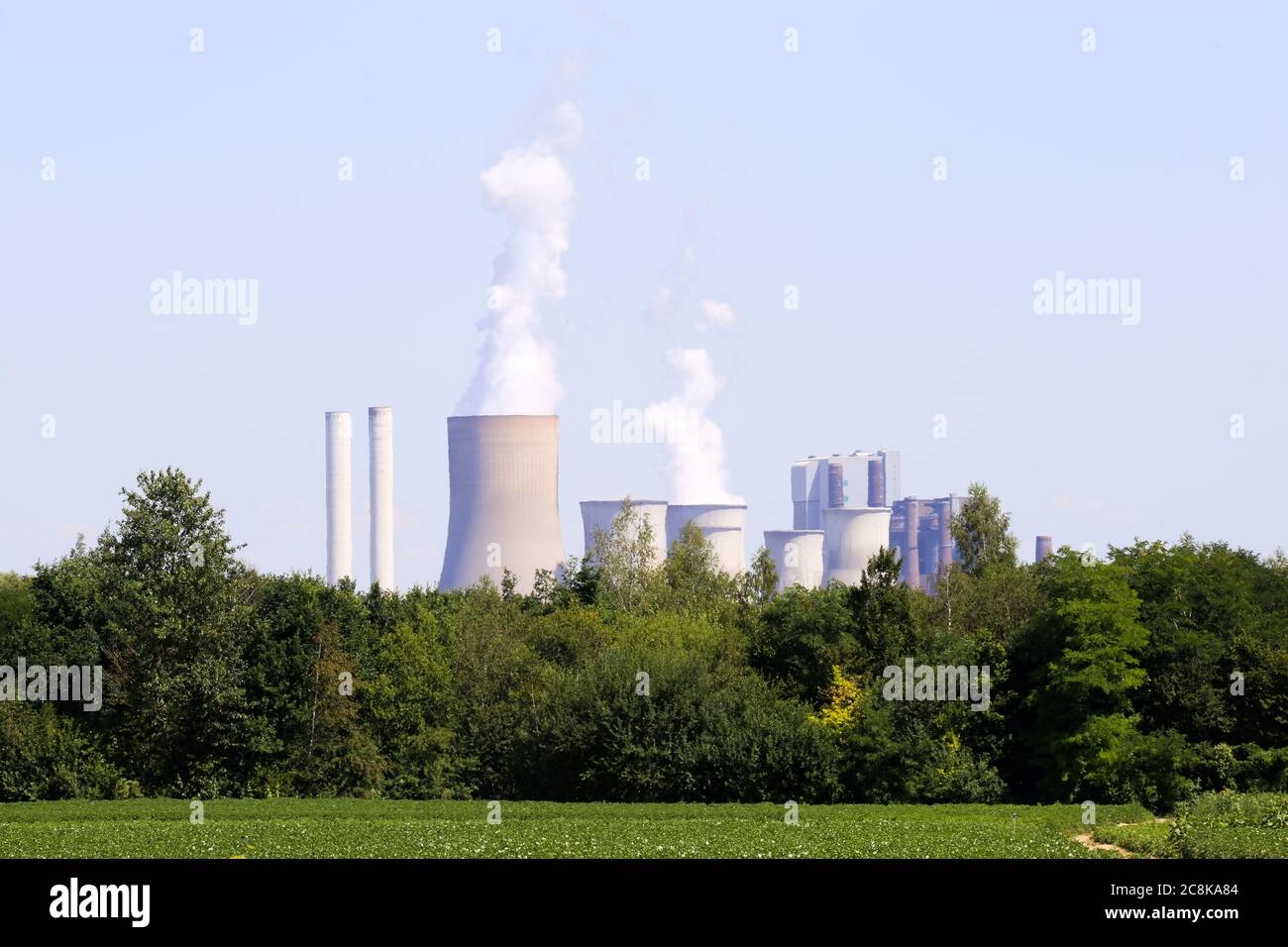 Grevenbroich, Deutschland - 9. Juli. 2020: Blick über Ackerfeld und Wald auf Braunkohlebergbau RWE Kraftwerk Frimmersdorf Stockfoto