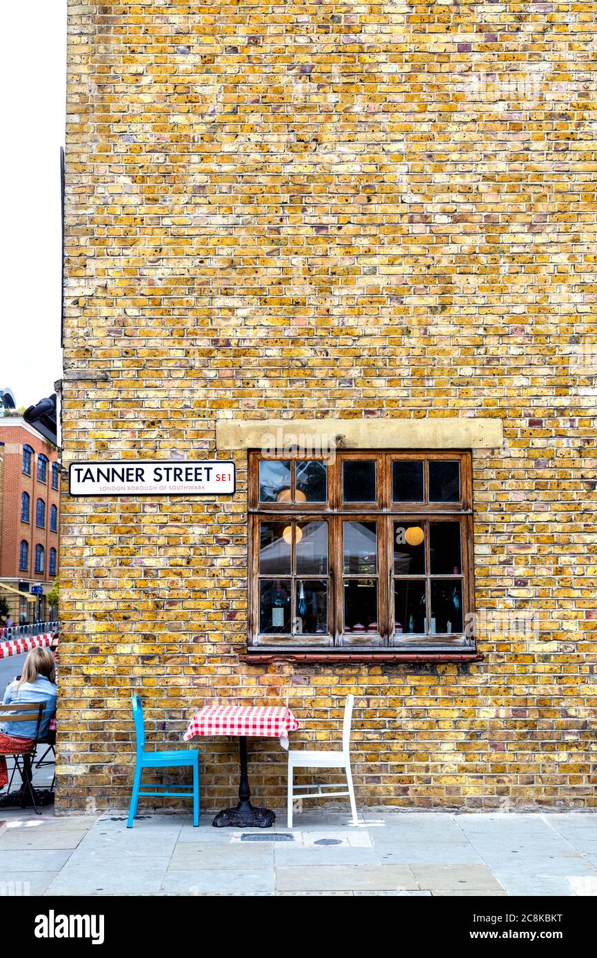Gelbe Ziegelwand an der Tanner Street, Sitzplätze im Freien im Casse Croute Restaurant, Bermondsey, London, Großbritannien Stockfoto