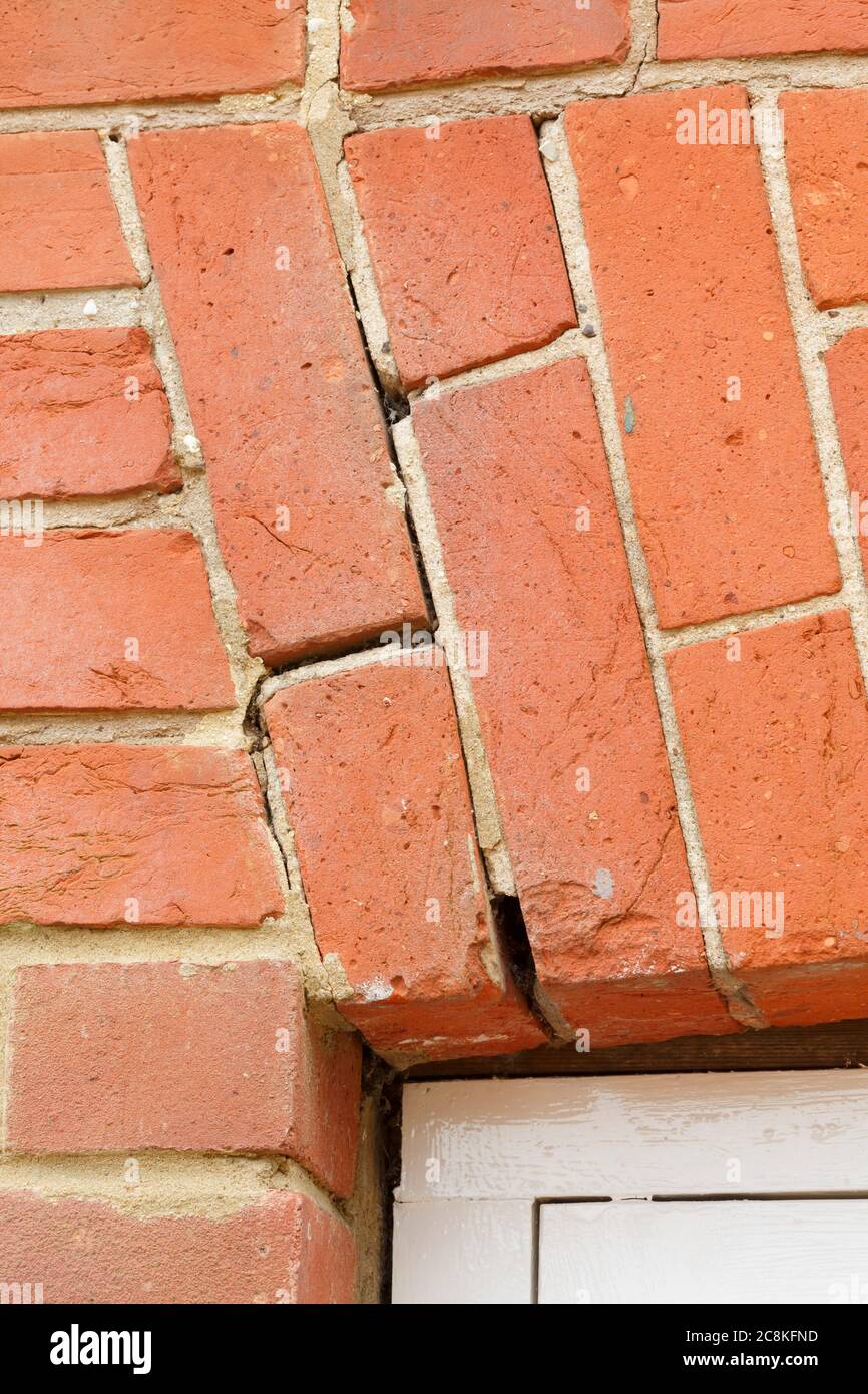 Gebrochener Ziegelbogen, rissiger Mörtel in Mauerwerk über einem Fenster in einem britischen Haus. Hauswartung und Reparaturen Stockfoto
