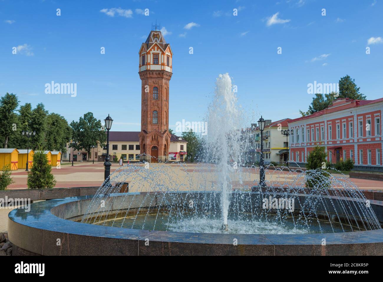 Stadtbrunnen vor dem Hintergrund eines alten Wasserturms an einem sonnigen Julimorgen. Staraya Russa, Russland Stockfoto