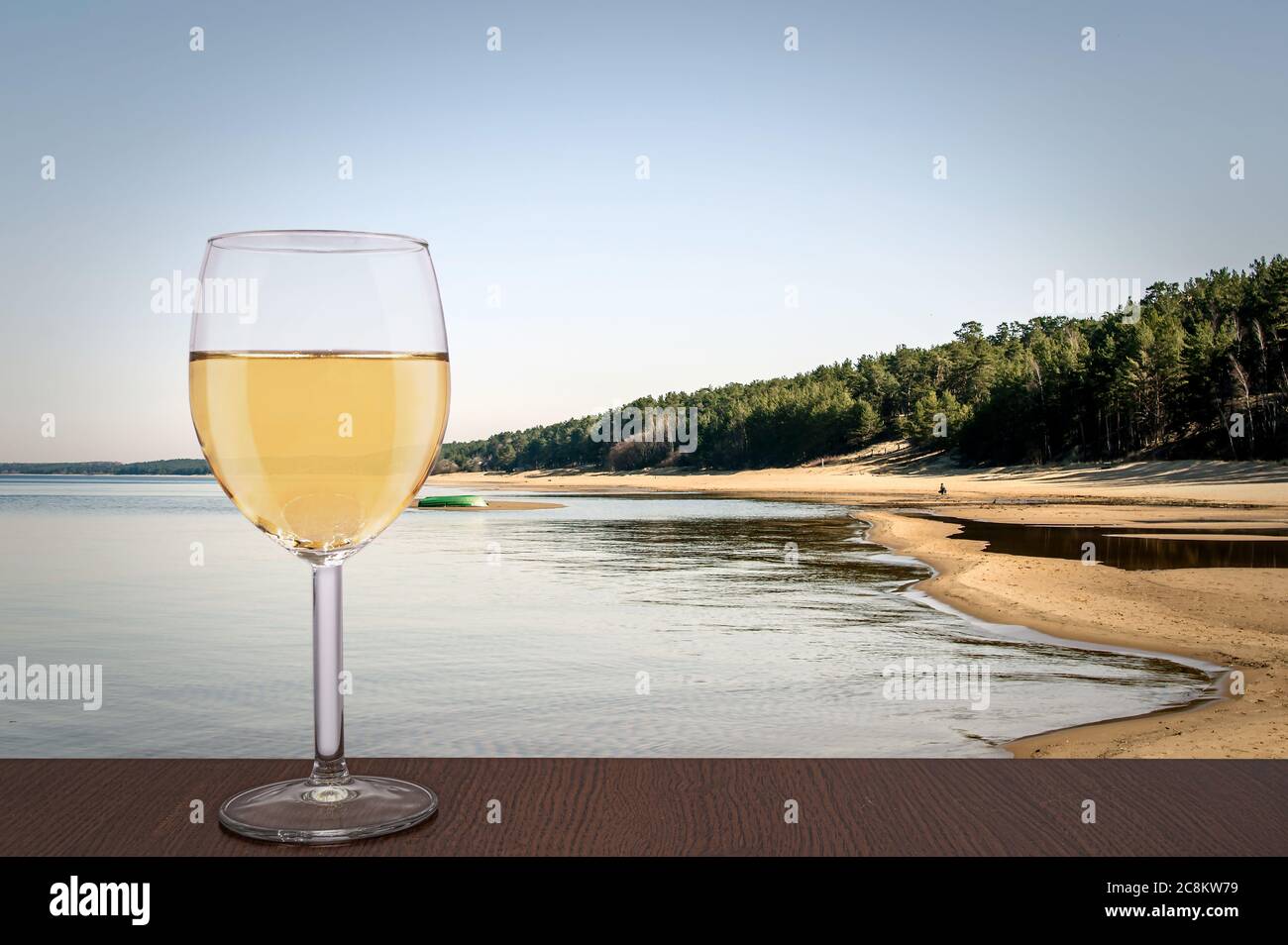 Ein Glas Weißwein mit Blick auf die Weiße Düne und den Baltischen See im Frühling, Lettland. Strand mit weißem Sand und blauem Meer. Strand mit Pinienwald Stockfoto