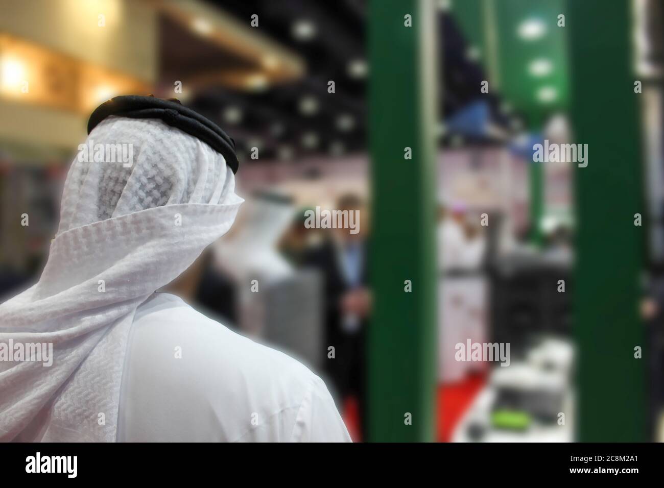 Arabischer Mann, der mit dem Rücken in einer Ausstellung steht. Unscharfer Hintergrund. Stockfoto