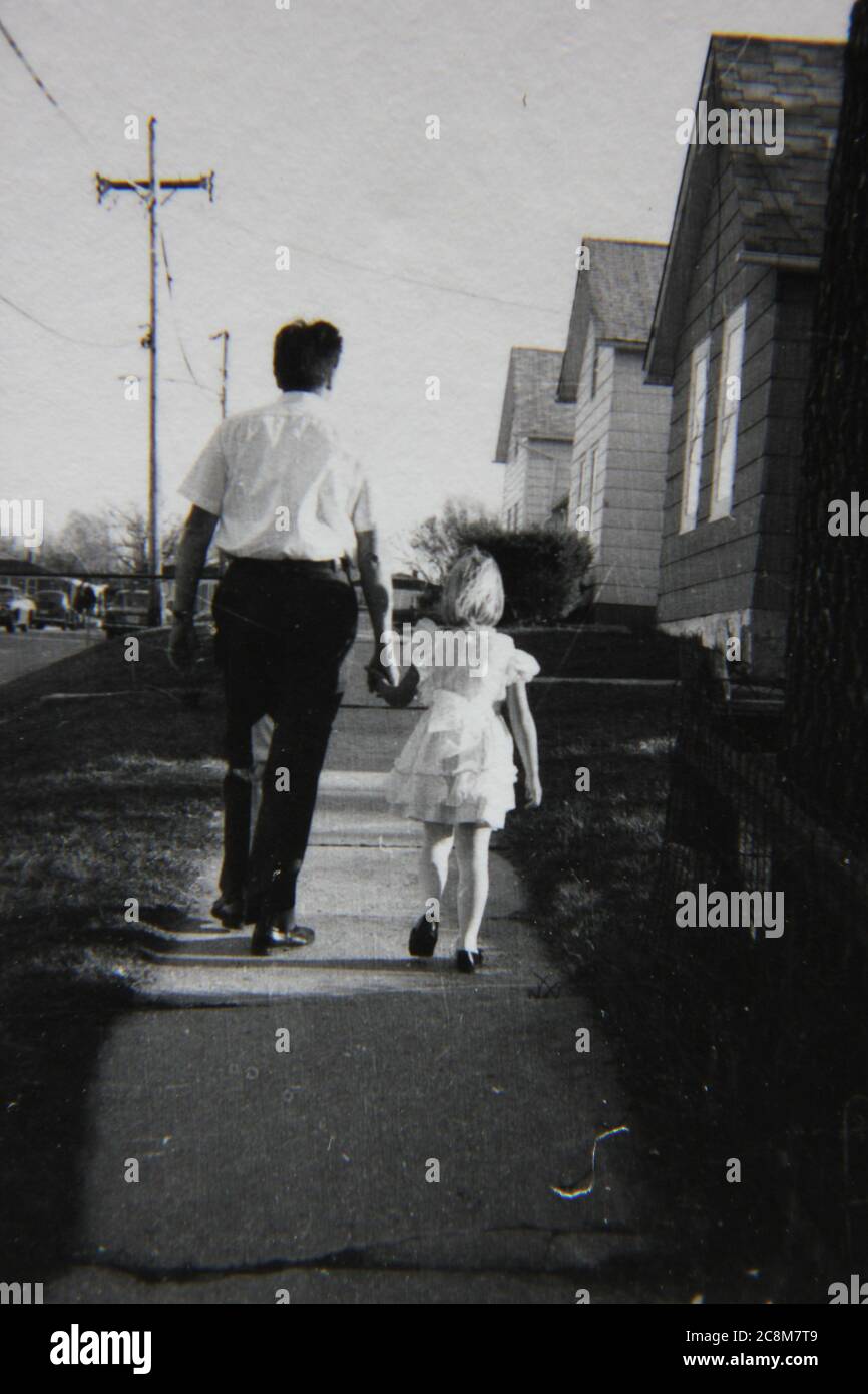 Feine 70er Jahre Vintage schwarz-weiß Lifestyle-Fotografie von einem Vater und Tochter verbringen Zeit miteinander auf dem Bürgersteig. Stockfoto