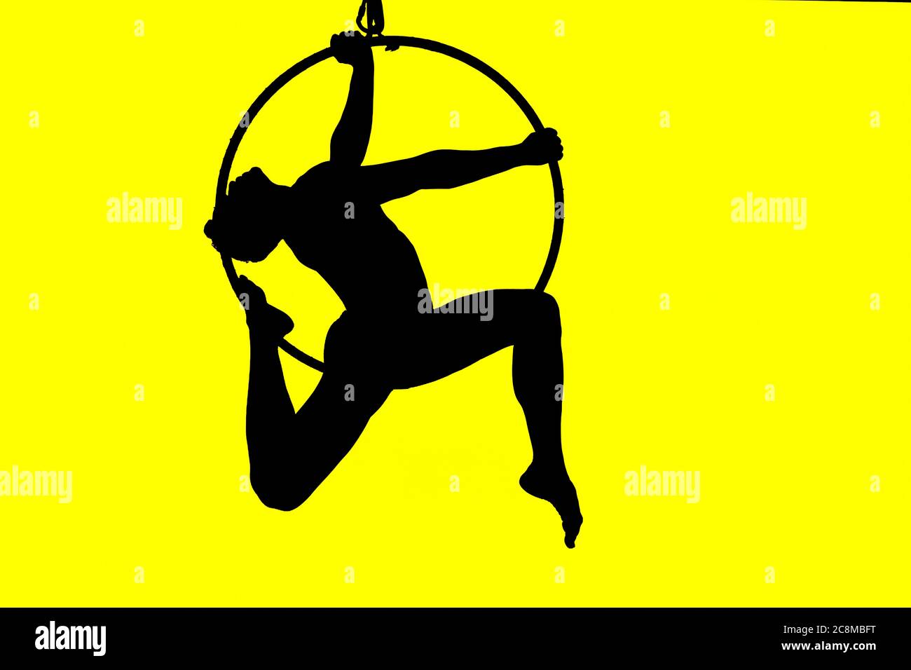 Silhouette des Menschen in hohen akrobatischen Reifen mit eleganten Pose und gelb beleuchteten Hintergrund Stockfoto