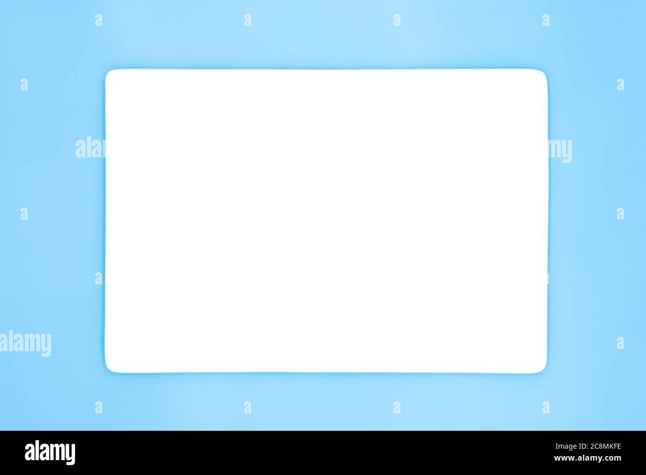 Eine leere, rechteckige weiße Platte, die auf dem hellblauen Hintergrund isoliert ist. Stockfoto
