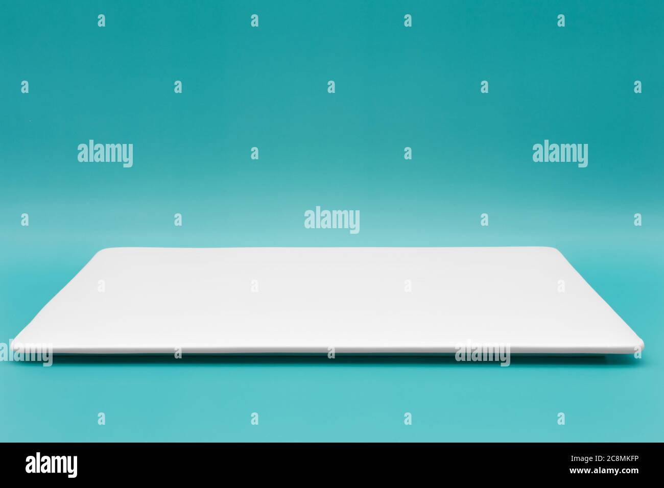 Eine leere weiße rechteckige Platte, isoliert auf dem blauen tiffany-Hintergrund. Stockfoto