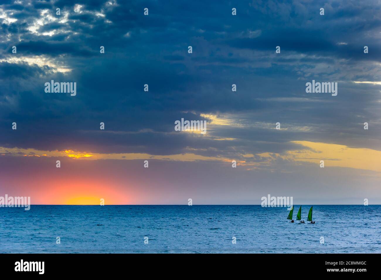 Goldener Sonnenuntergang am wunderschönen Brighton Beach in Adelaide, Südaustralien, während drei Segelboote sich auf den Sonnenuntergang am südlichen Ozean zubewegen. Stockfoto