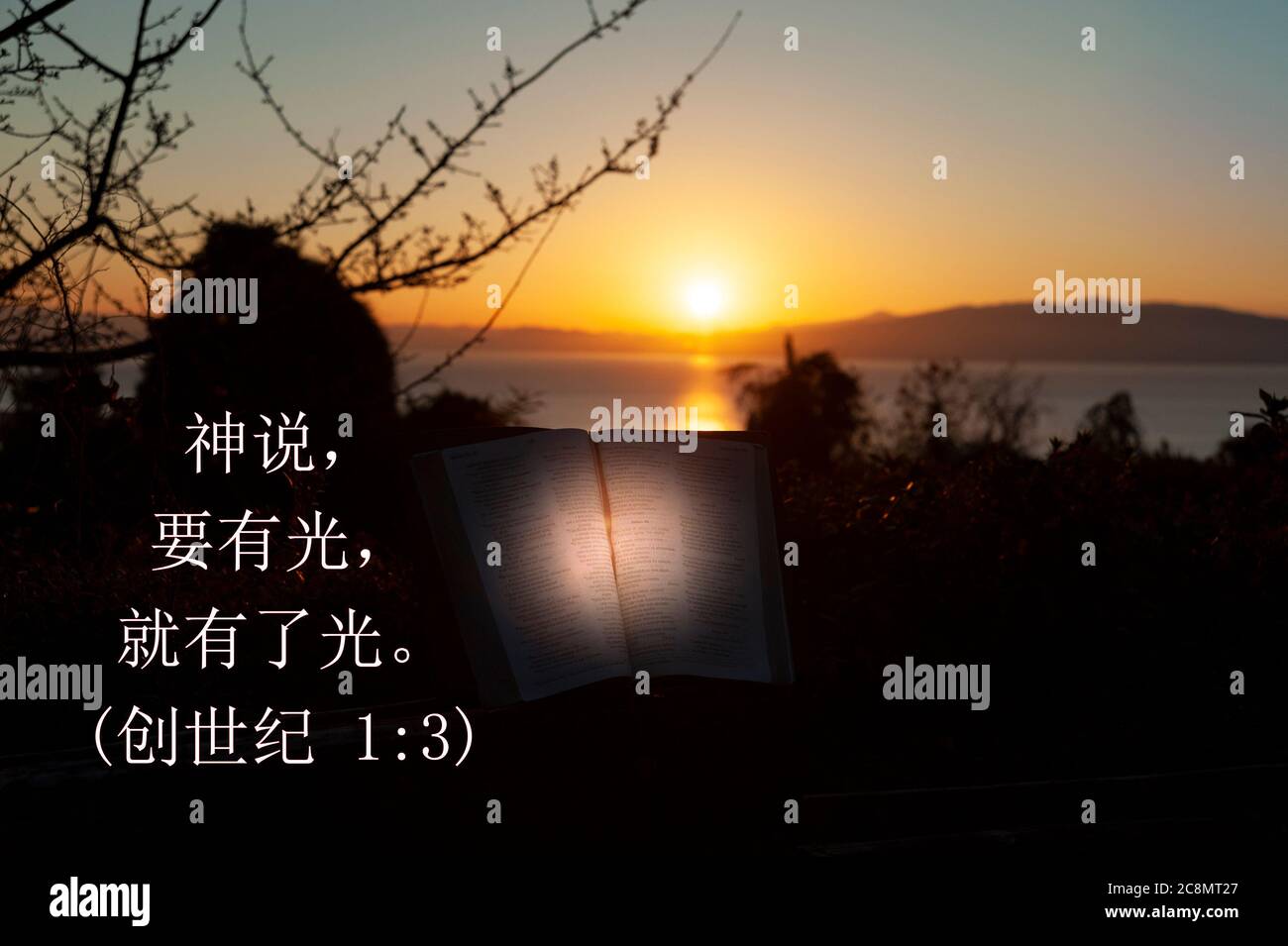 Heilige Bibel mit gerichtetem Licht geöffnet. Hintergrund mit Meer, goldenem Himmel und Sonnenaufgang hinter den Bergen. Text in chinesischen Zeichen aus Gen 1:3. Stockfoto