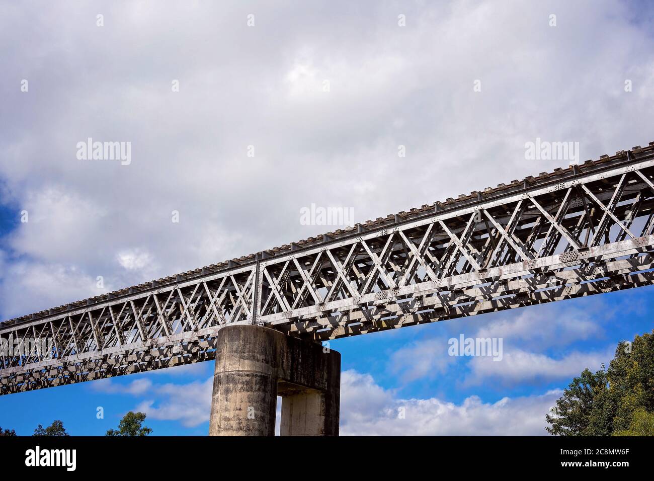 Eine Eisenbahnbrücke aus Beton und Stahl gegen einen wolkigen blauen Himmel Stockfoto