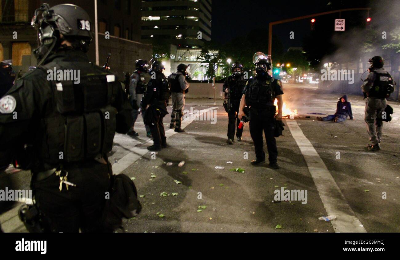 Portland, Oregon, USA. Juli 2020. Ein Polizeimann tritt selten auf, seit die Feds ihre Zuständigkeit übernommen haben: Seine Geschwader sind damit beauftragt, die Feuerreste zu säubern, da sie sich vor dem Tor des Gerichtshauses befinden. Es gibt Verwirrung darüber, wo die Presse stehen soll, aber sie lassen die Medien bleiben, während sie den Bereich von Protestierenden lange genug freihalten, um sie zu reinigen. Portland Proteste wachsen und Chaos verschärft sich Kredit: Amy Katz/ZUMA Wire/Alamy Live News Stockfoto