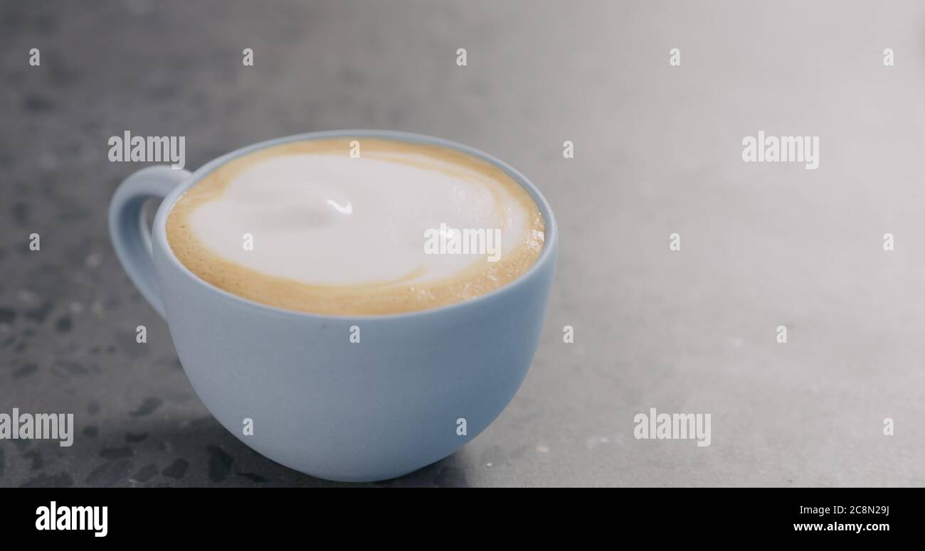 Cappuccino in blauer Tasse auf Beton Hintergrund Stockfoto