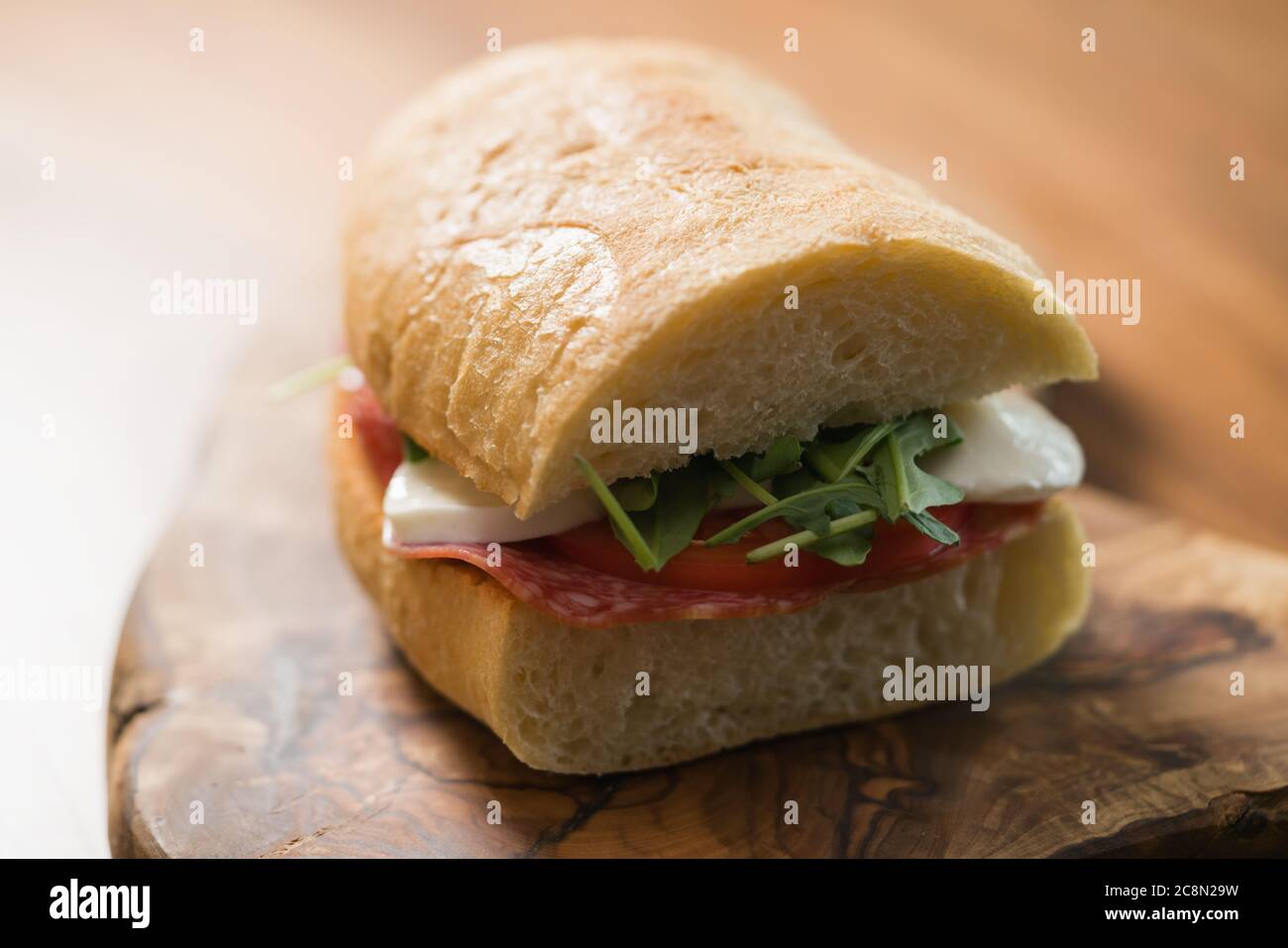 Ciabatta Sandwich mit Salami und Mozzarella Käse auf Walnusstisch Stockfoto