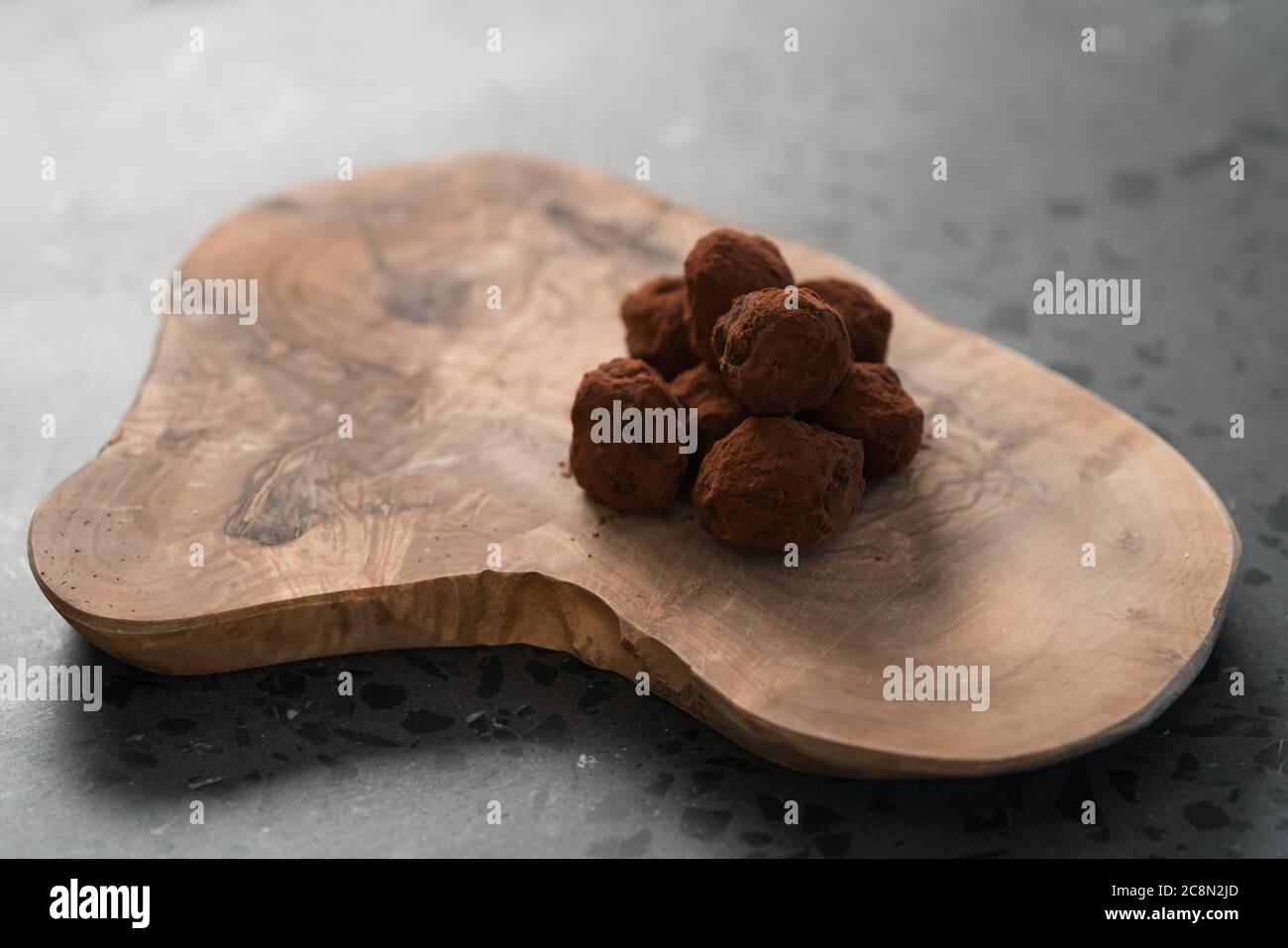 Handgemachte Schokoladentrüffel auf olivfarbenem Brett Stockfoto
