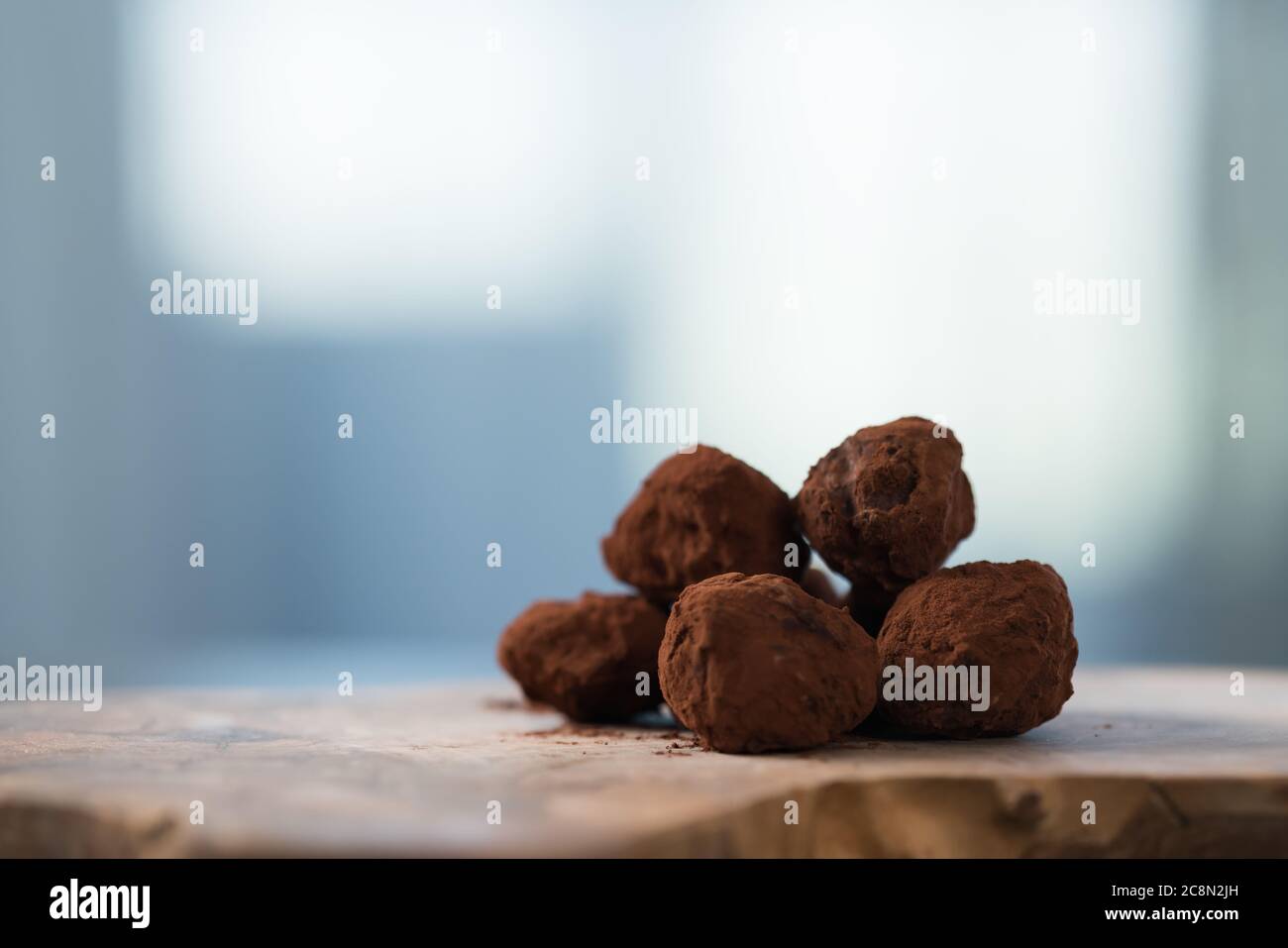 Handgemachte Schokoladentrüffel auf olivfarbenem Brett Stockfoto