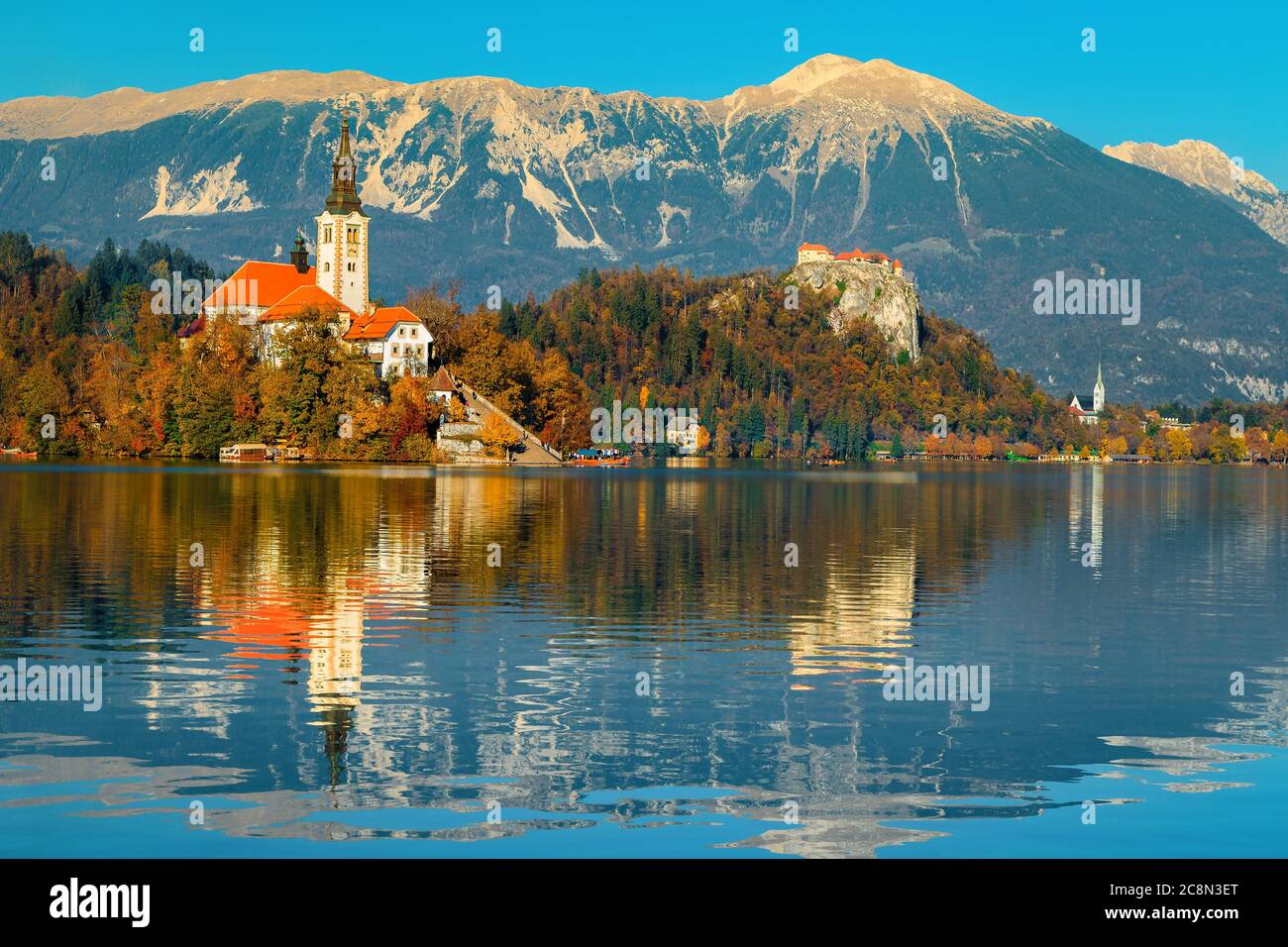 Herbstlandschaft mit Bleder See. Cute Wallfahrtskirche am Ufer des Sees und spektakuläre Festung auf den Klippen im Hintergrund, Bled, Slowenien, EUR Stockfoto
