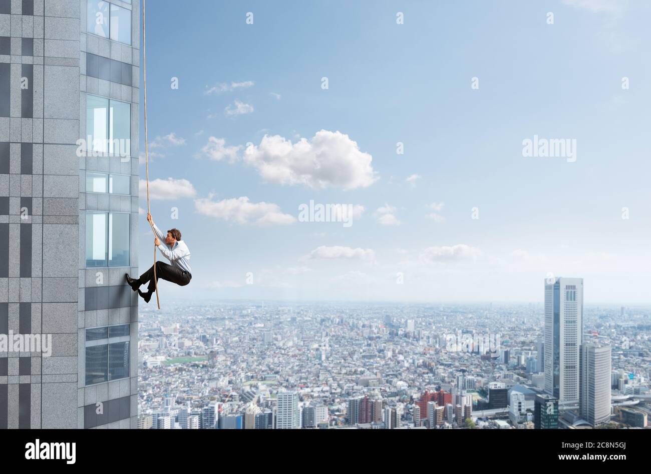 Geschäftsmann steigt mit einem Seil ein Gebäude an. Konzept der Bestimmung. Stockfoto