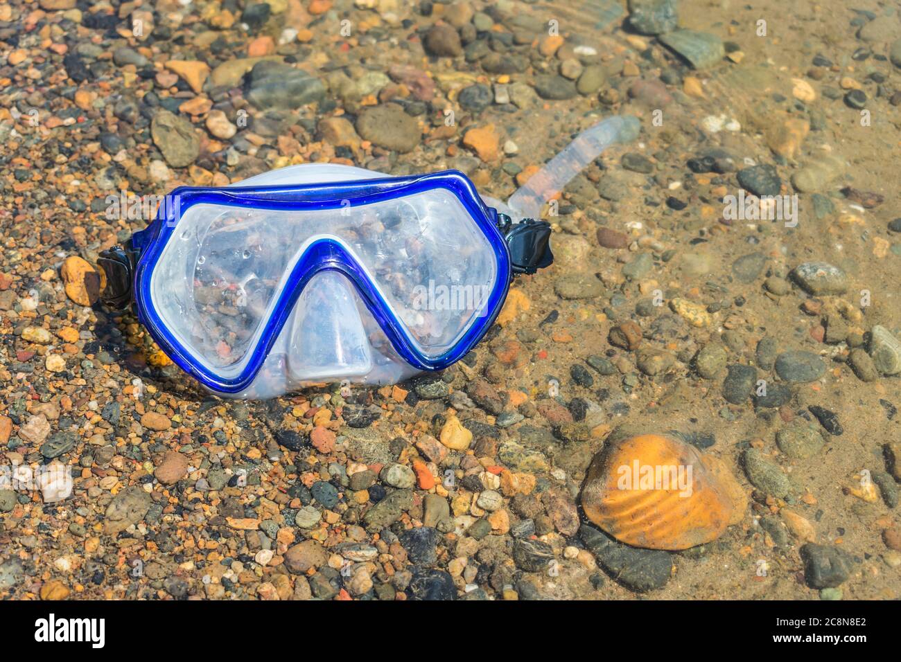 Die verlorene Schnorchelmaske liegt im Wasser auf kleinen Steinen Stockfoto