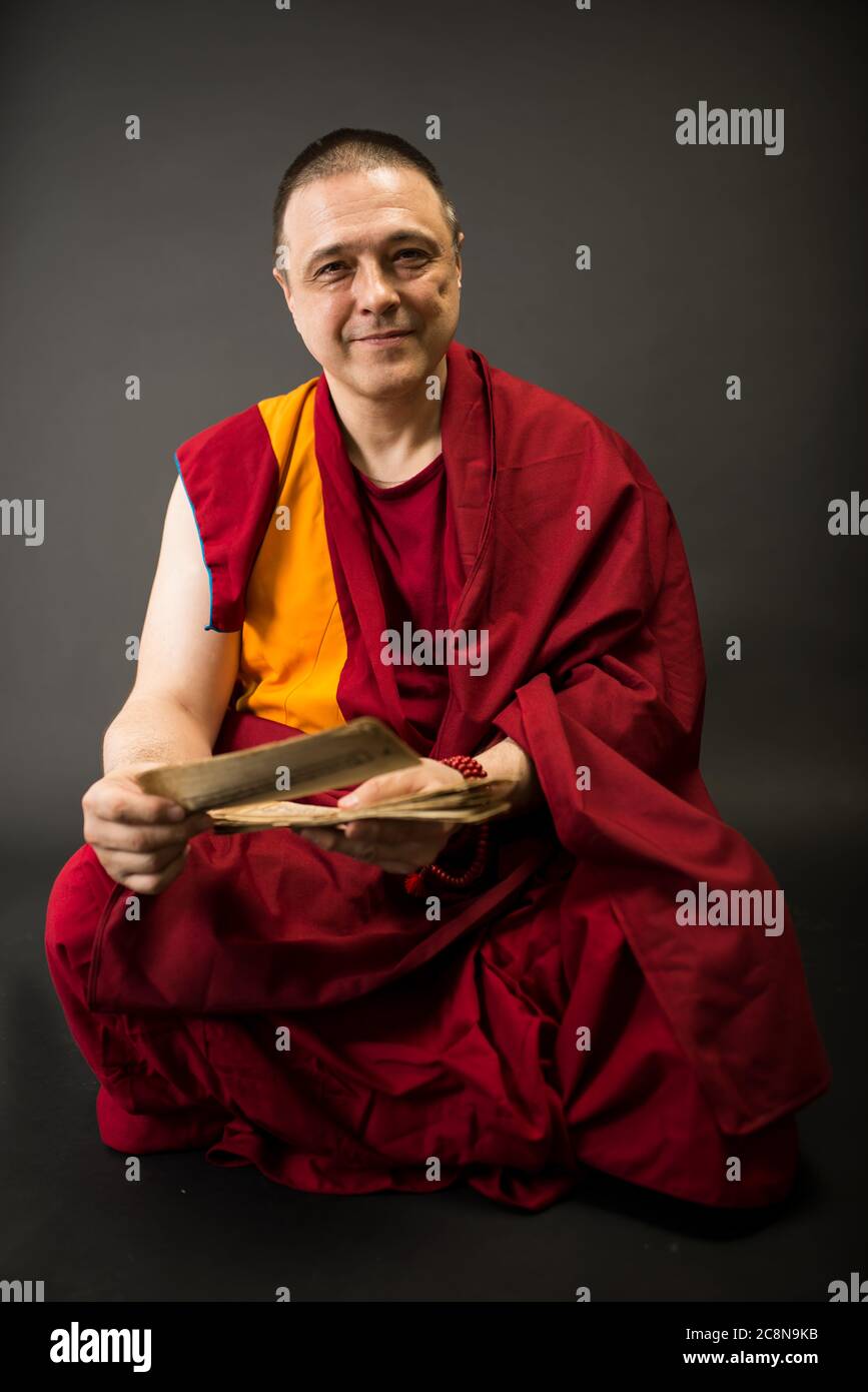 Buddhistischer Mönch in rotem Kleid mit Gebetstexten und Mantras in der Hand Stockfoto