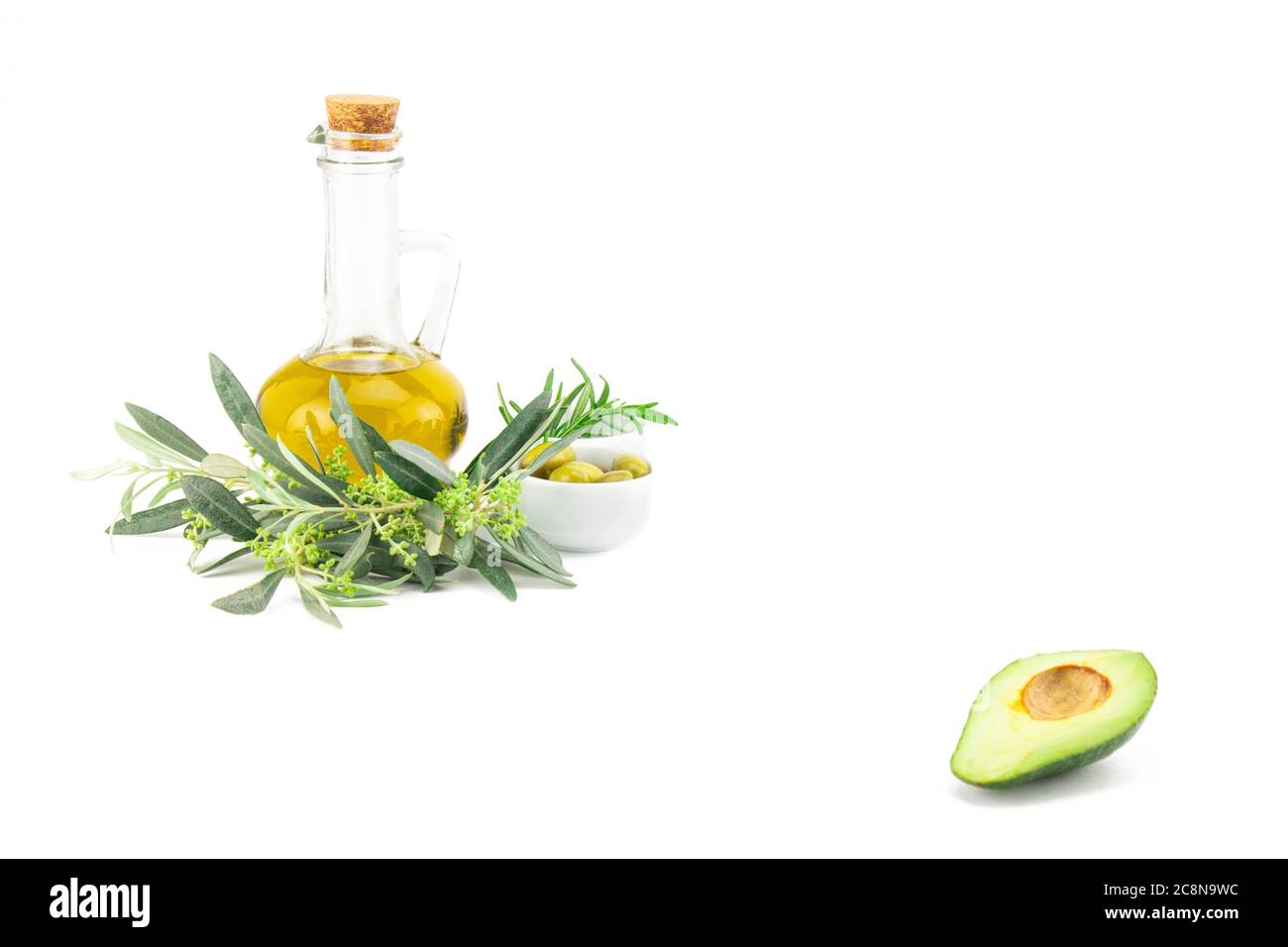 Glasflasche mit nativem Olivenöl Premium, Avocado und einige Oliven mit Olivenzweig isoliert auf weißem Hintergrund Stockfoto