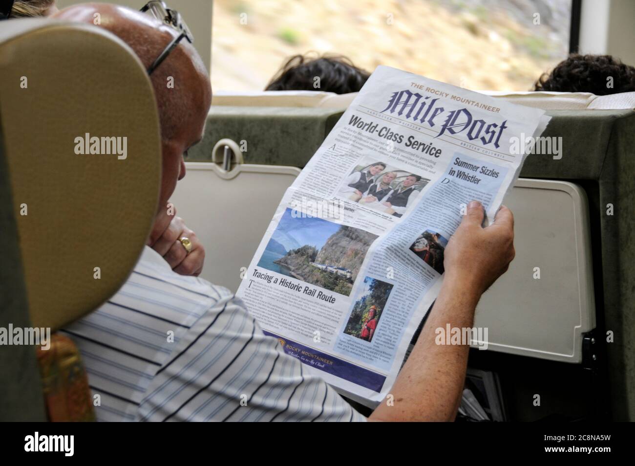 Ein Passagier liest die Rocky Mountaineer Zugzeitung. Kanada. Stockfoto