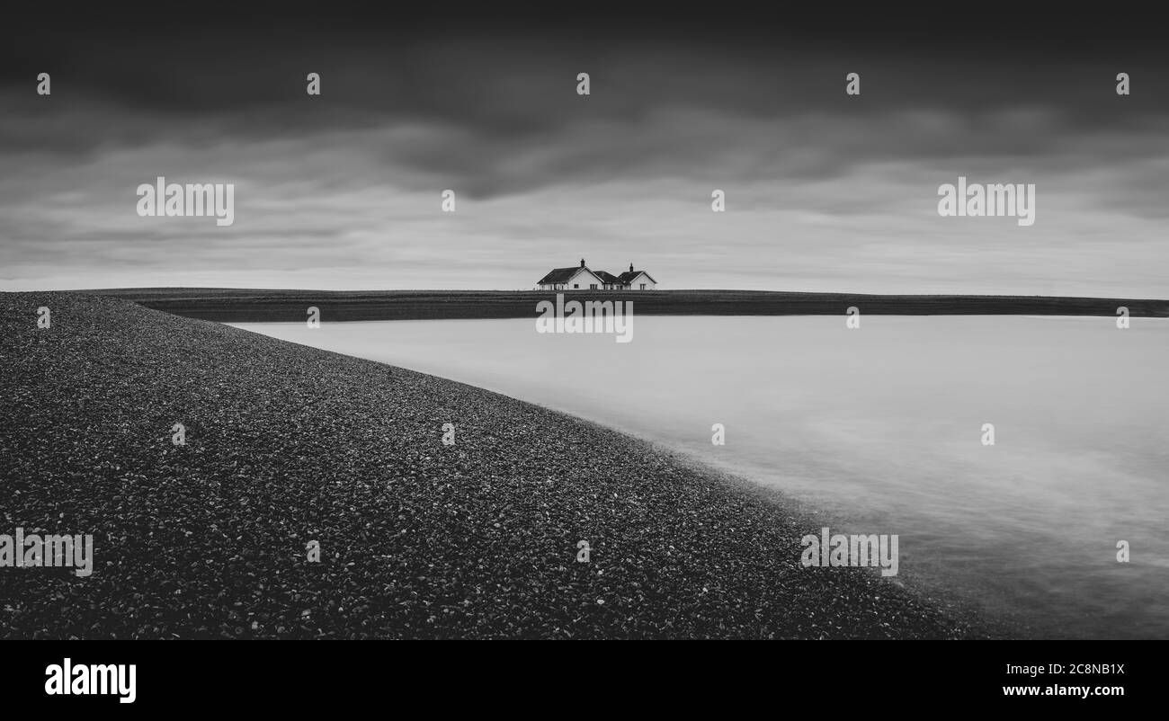 Ein einfamilienhaus auf einem Schindelufer bei Flut. Stockfoto