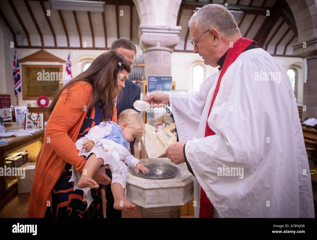 Rev Canon Joe Morrow führt die erste Post-Lockdown-Taufe in der Scottish Episcopal Church des 11 Monate alten Magnus Hutchwaite, mit seinen Eltern Jeremy und Pamela Hutchwaite, in St. James der große Kirche in Stonehaven. Stockfoto