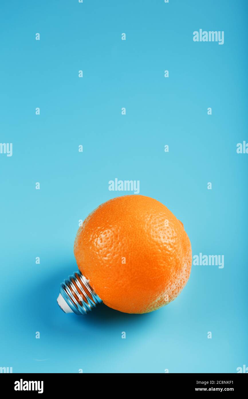 Orangefarbene Glühlampe auf blauem Hintergrund. Das Konzept der Fruchtideen Stockfoto