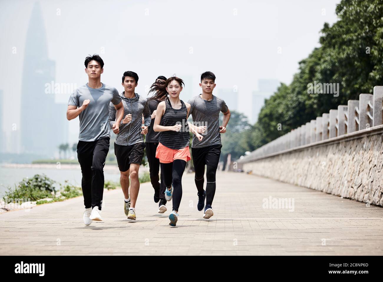 Gruppe von fünf jungen asiatischen erwachsenen Männern und Frauen laufen Training im Freien Stockfoto