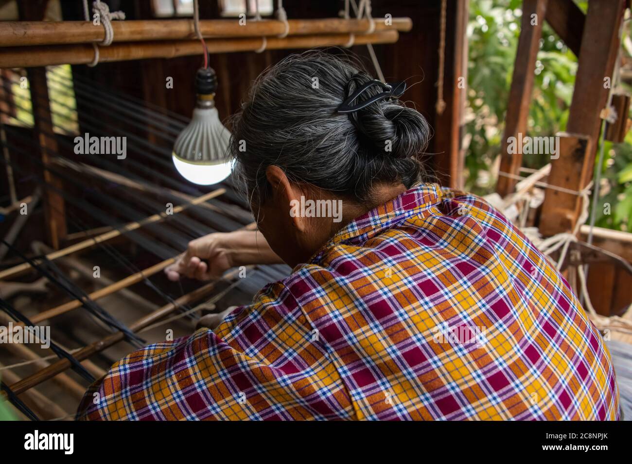 Inle Lake, Myanmar - Februar 2020: Asiatische Frau webt Stoff auf einem traditionellen Holzwebstuhl im Dorf. Stockfoto