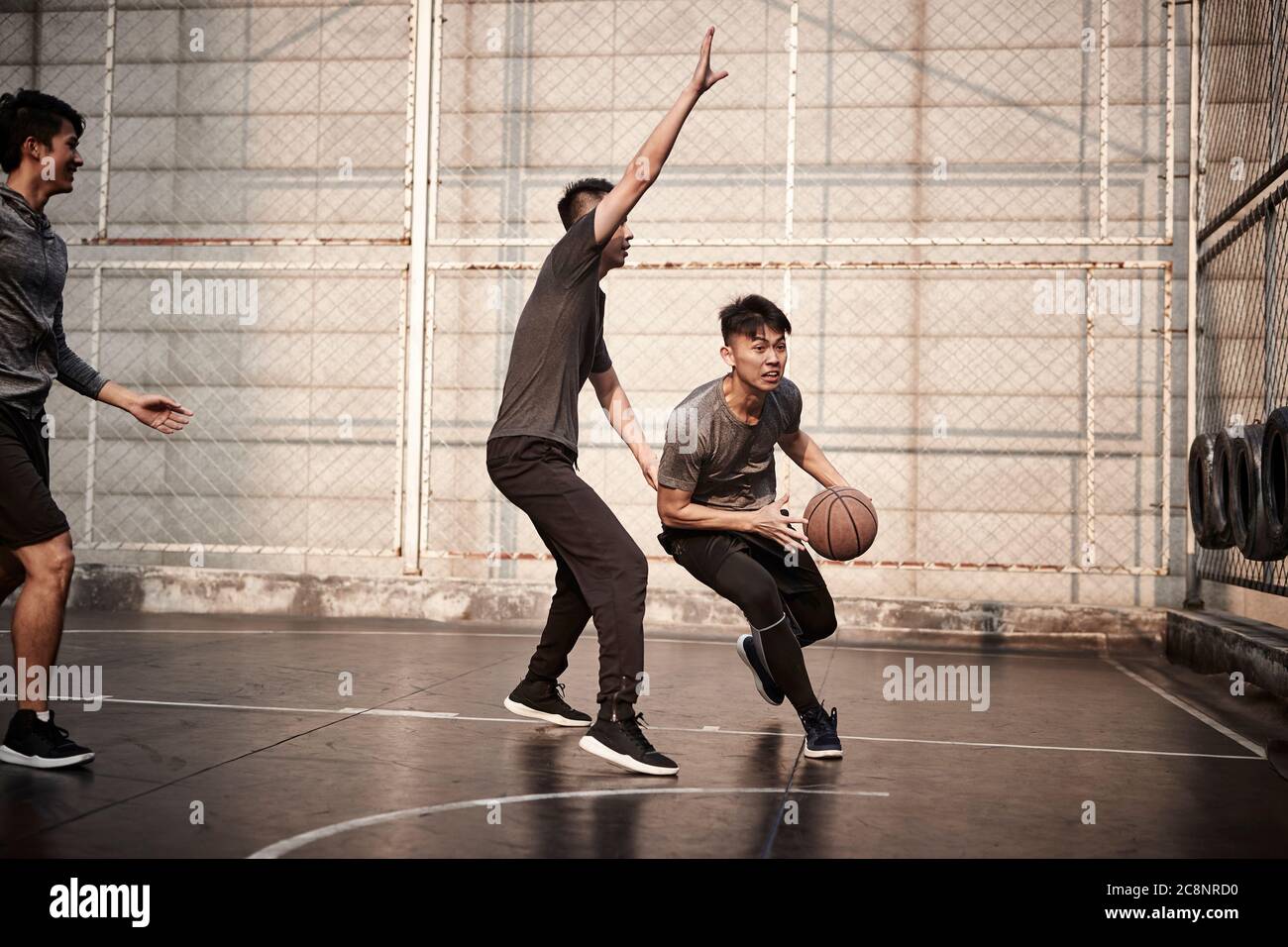 Junge asiatische Erwachsene Männer spielen Basketball auf dem Freiplatz Stockfoto