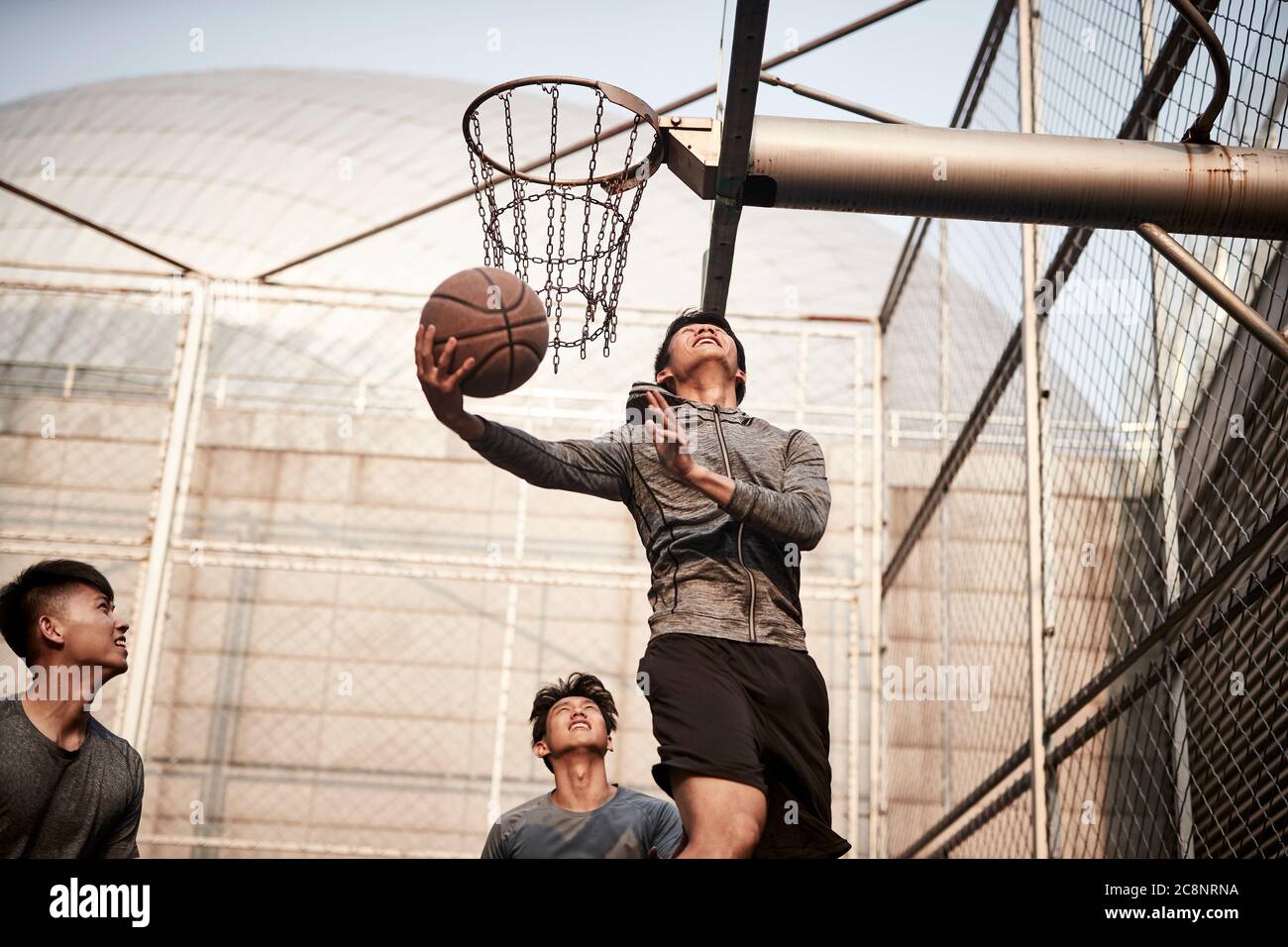 Junge asiatische Erwachsene Männer spielen Basketball auf dem Freiplatz Stockfoto