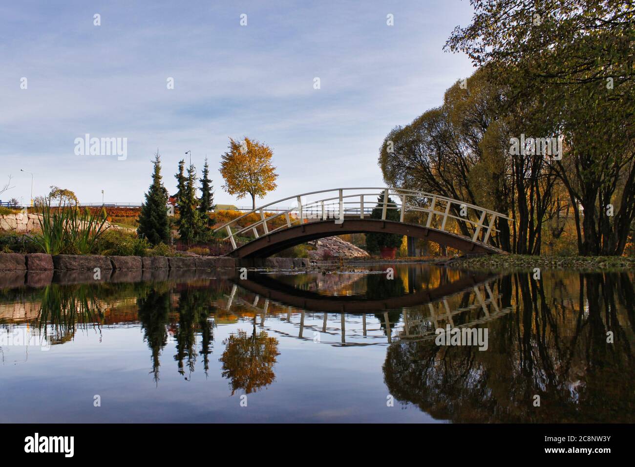 Landschaft von arced Brücke über Teich mit Reflexionen auf Wasser. Standort Kotka, Finnland Stockfoto