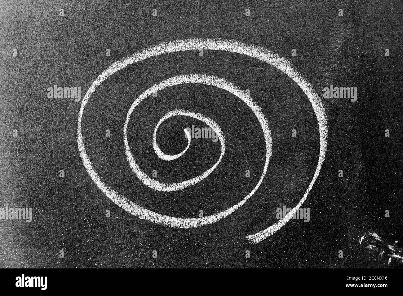 Weiße Kreidehandzeichnung in Spiralform auf schwarzem Bretterhintergrund Stockfoto