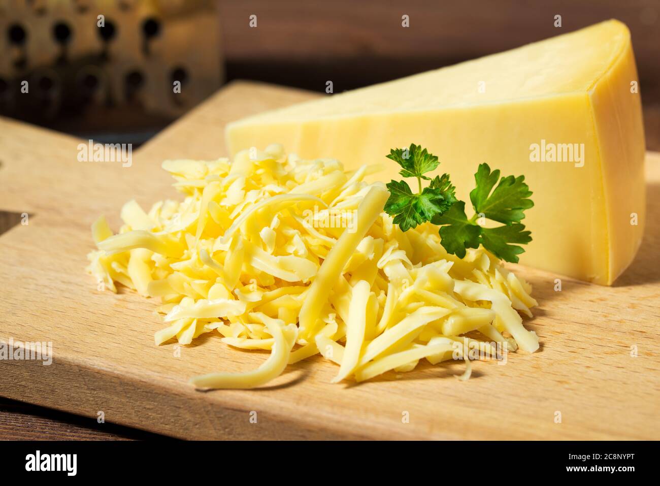 Geriebener Käse und Käse Dreieck auf Holz Schneidebrett Stockfoto