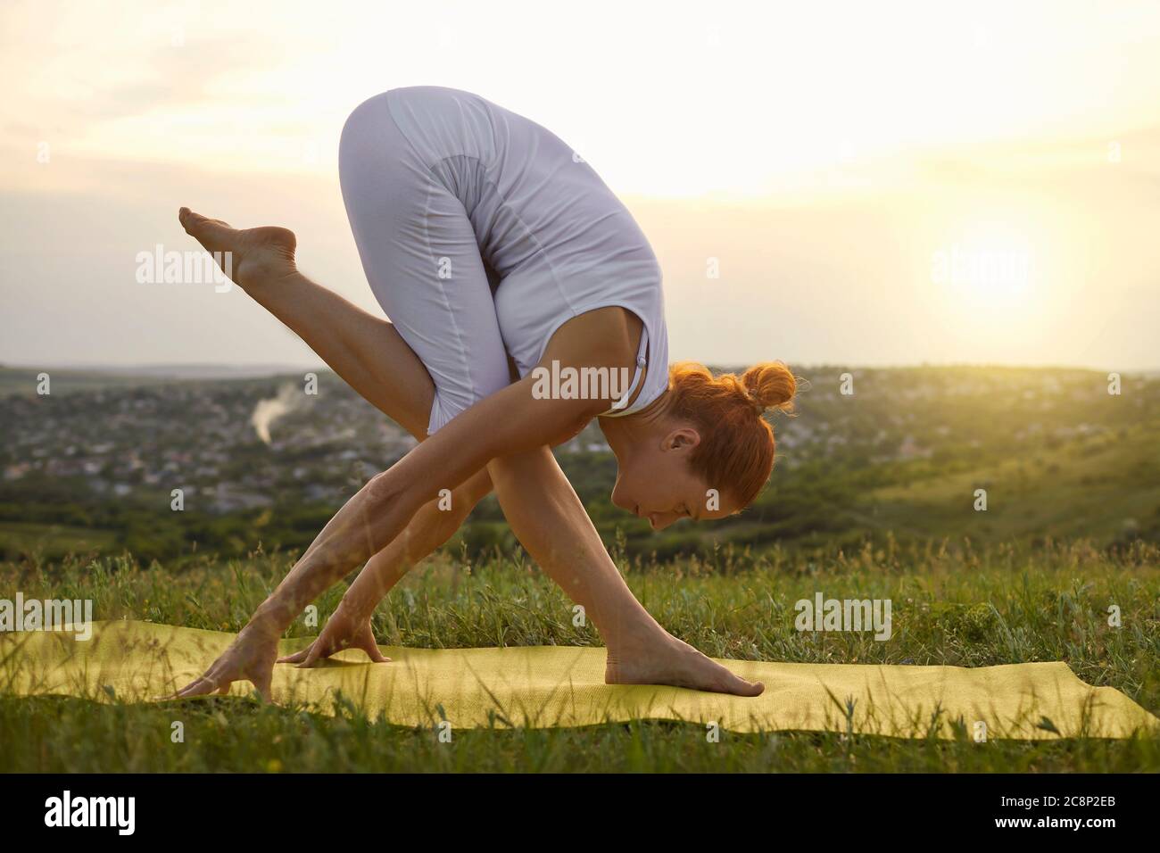 Erwachsene Frau, die Yoga während Sonnenuntergang in der Natur macht Stockfoto