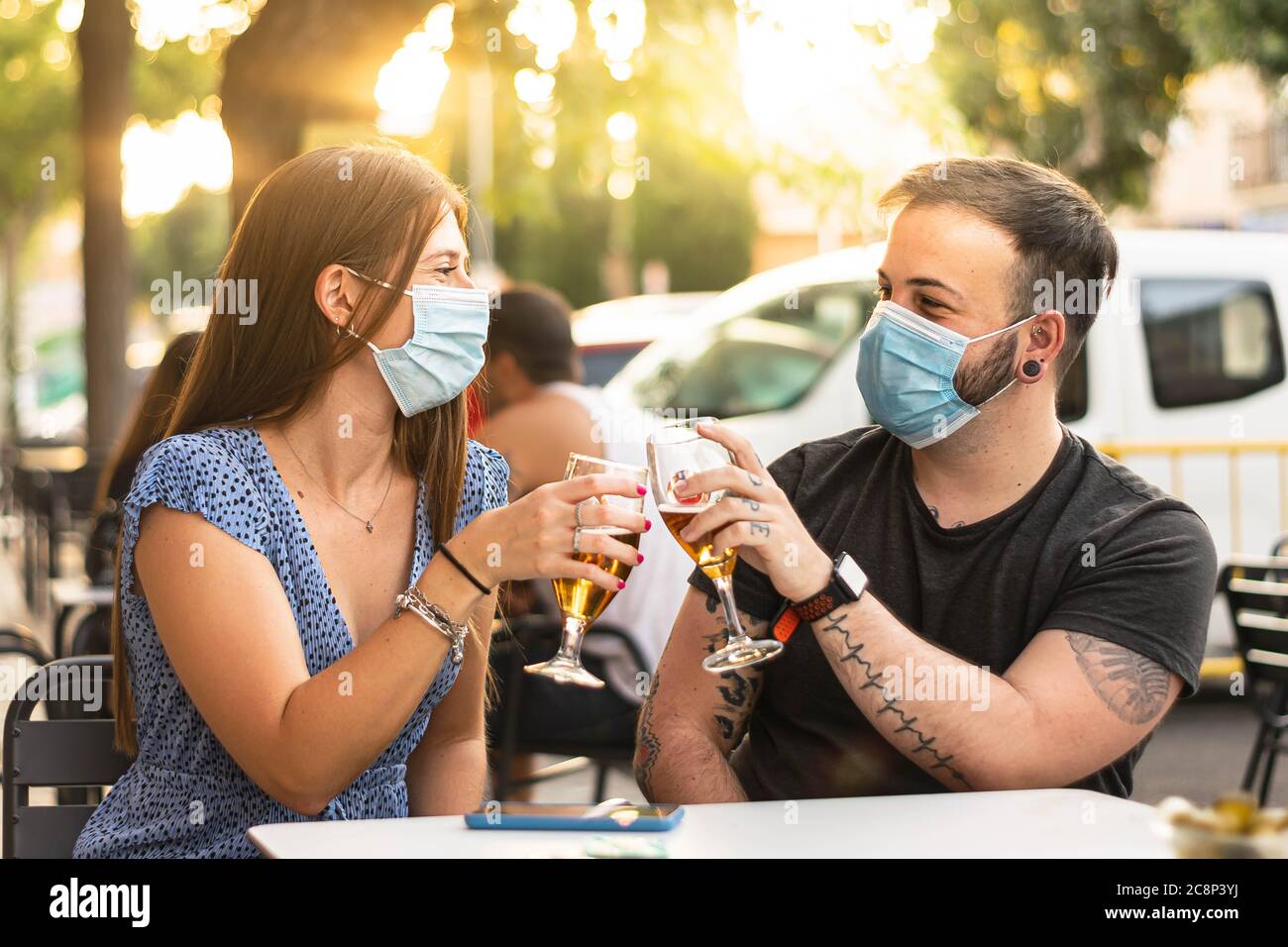 Spanien Madrid. Kaukasische Paar Toasten mit Bier tragen Sanitärmaske. Öffnen Sie die Pubs und den Club nach dem Quarentin-Coronavirus Covid-19 wieder. Stockfoto