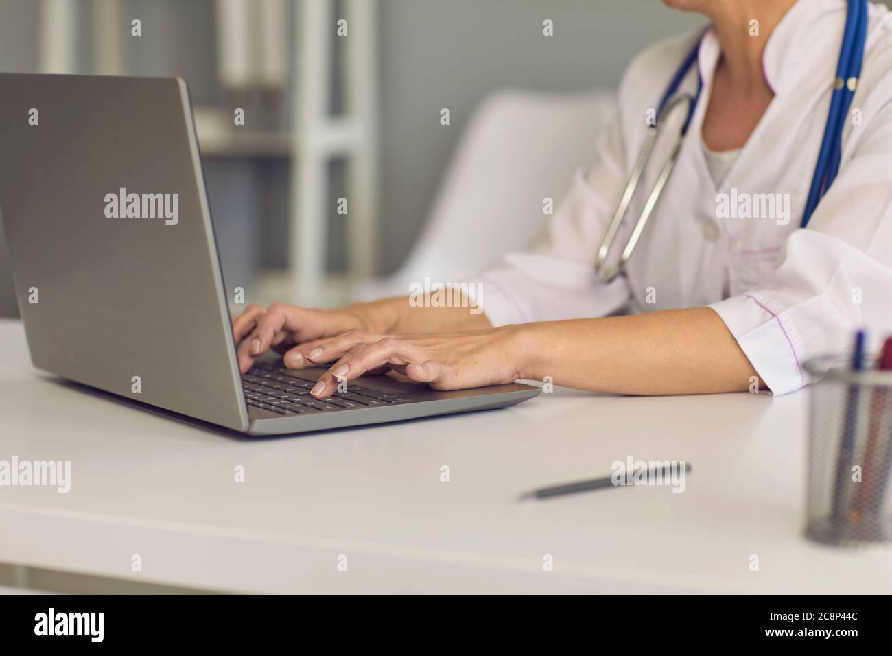 Konzept Arzt online. Arzthand tippen auf einem Laptop Tastatur eine Nachricht Web-Chat Beratung medizinische Klinik. Stockfoto